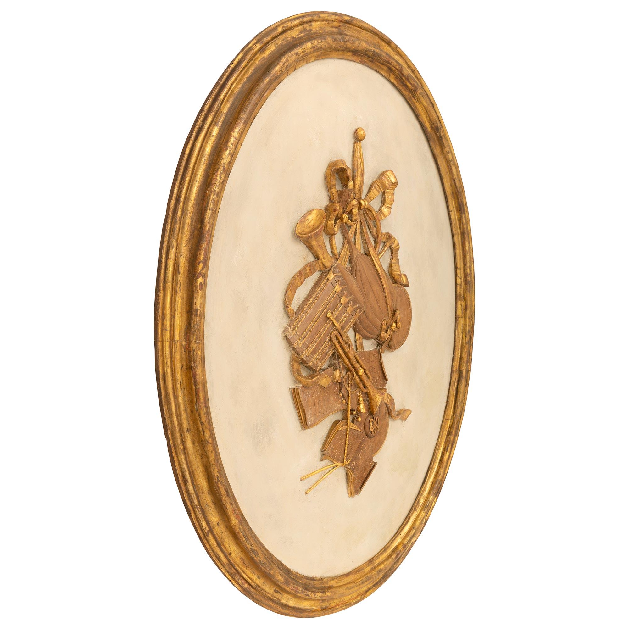 A charming and extremely decorative true pair of Italian 18th century Louis XVI period patinated wood and Mecca wall plaques. Each large scale oval plaque is framed within an elegant mottled Mecca border centering the beautiful patinated off white