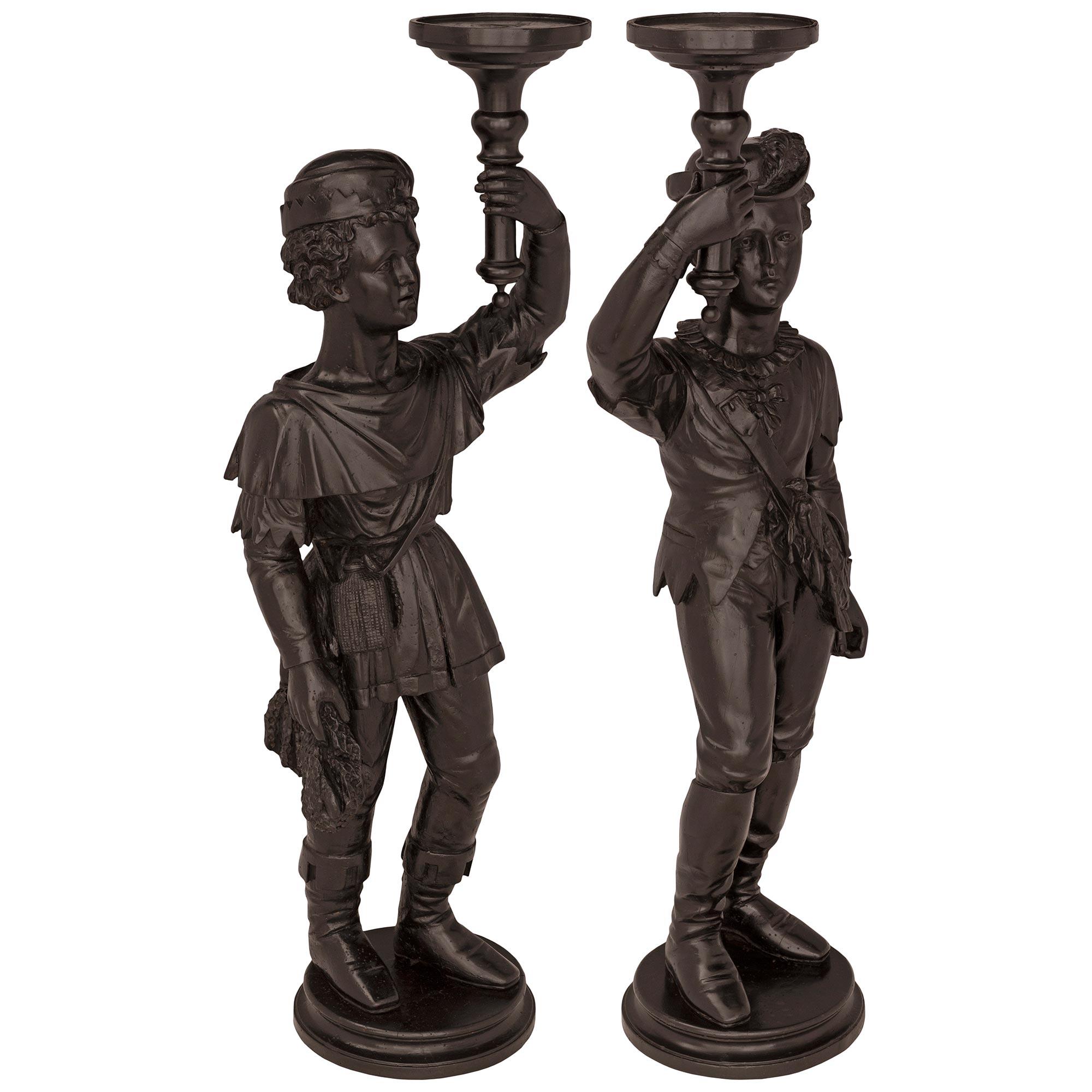 A beautiful and extremely decorative true pair of Italian 18th century Venetian st. ebonized Fruitwood candle/plant stands. Each striking stand depicts a charming young gondolier standing on a circular base with a fine mottled border. Each gondolier