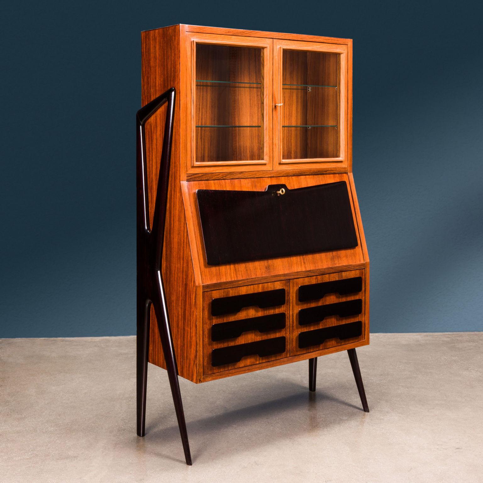 Trumeau designed by Ico Parisi for a 1940s Fratelli Rizzi production.

Characterized by two outer side uprights, with organic shape.
The cabinet has an upper compartment, with shelves, closed by glass doors; a shaped, ebony-stained wood writing desk