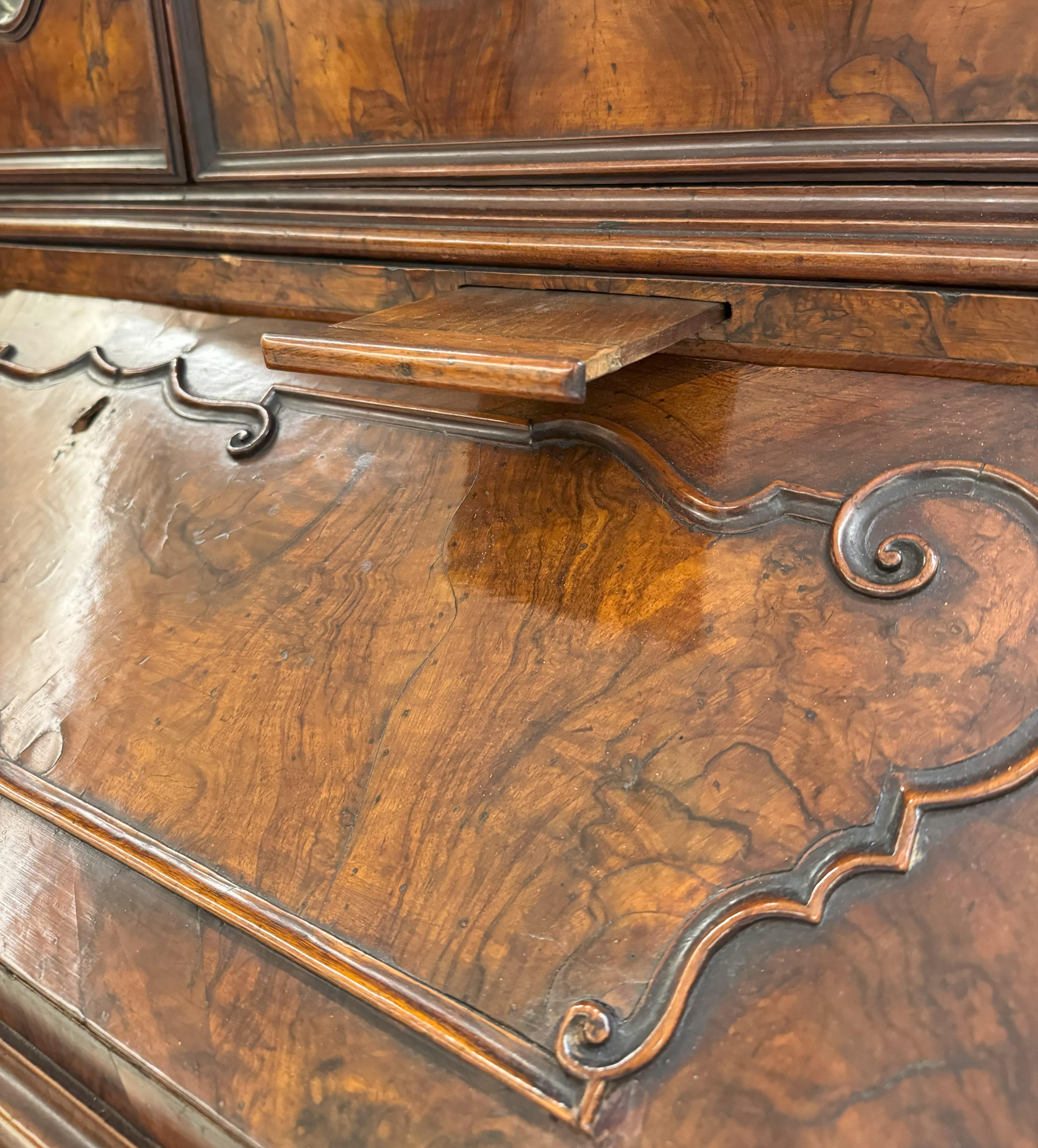 Trumeau lastronato in radica, Lombardia, XVIII secolo, decorato da cornicette in rilievo a formare riserve sagomate, fronte a tre cassetti mossi, tiretti portacandele, anta a ribalta celante segreto e cassettini a doppia mossa, montanti intagliati a