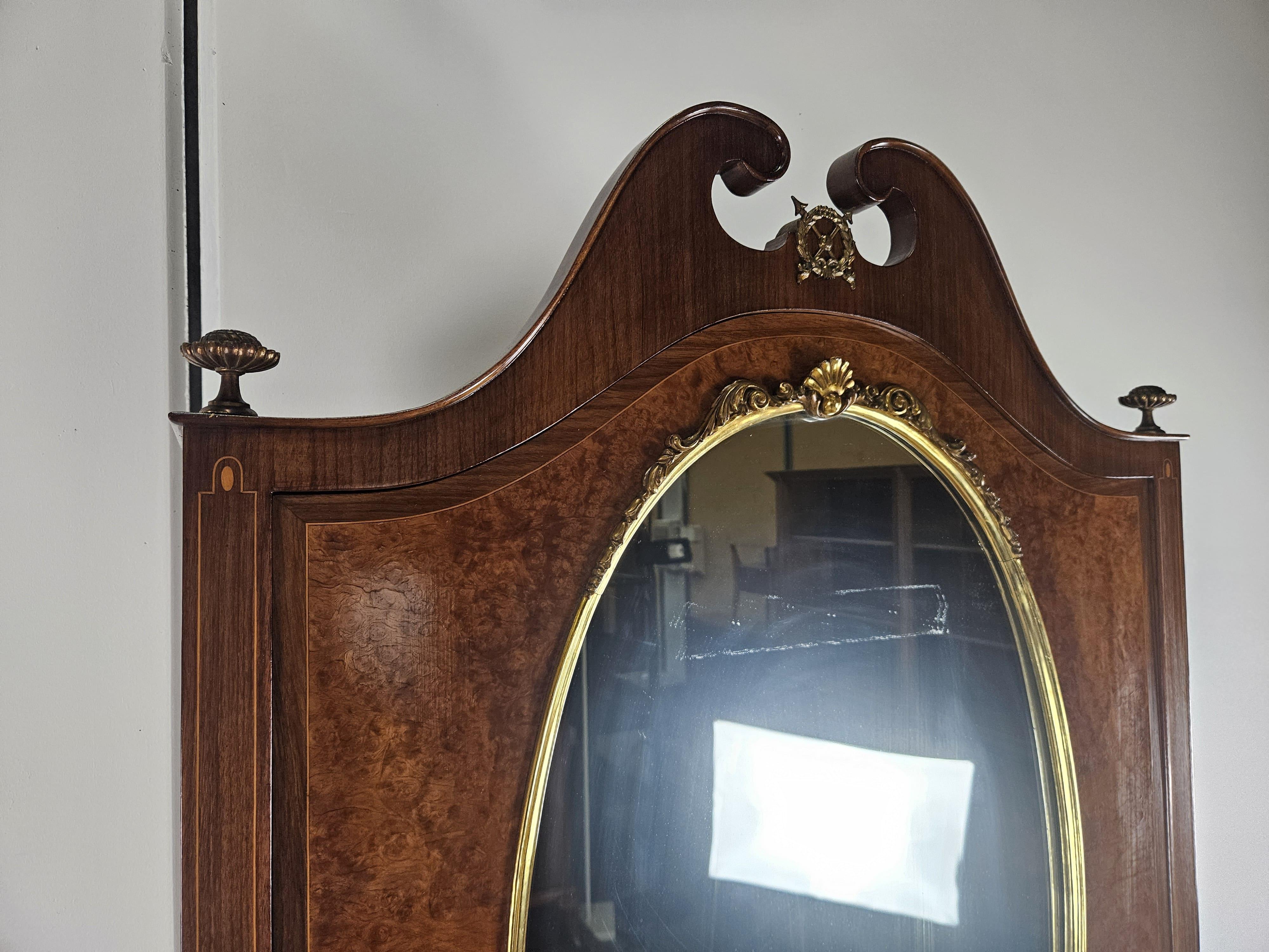 Elegantes Trumeau aus der Mitte des zwanzigsten Jahrhunderts mit Intarsien aus Nussbaum, Ahorn und Messingdekorationen. Ein repräsentatives Möbelstück, das jeden Raum aufwertet.

Das Trumeau ist ein klassischer Doppelkorpus mit einer oberen Tür und