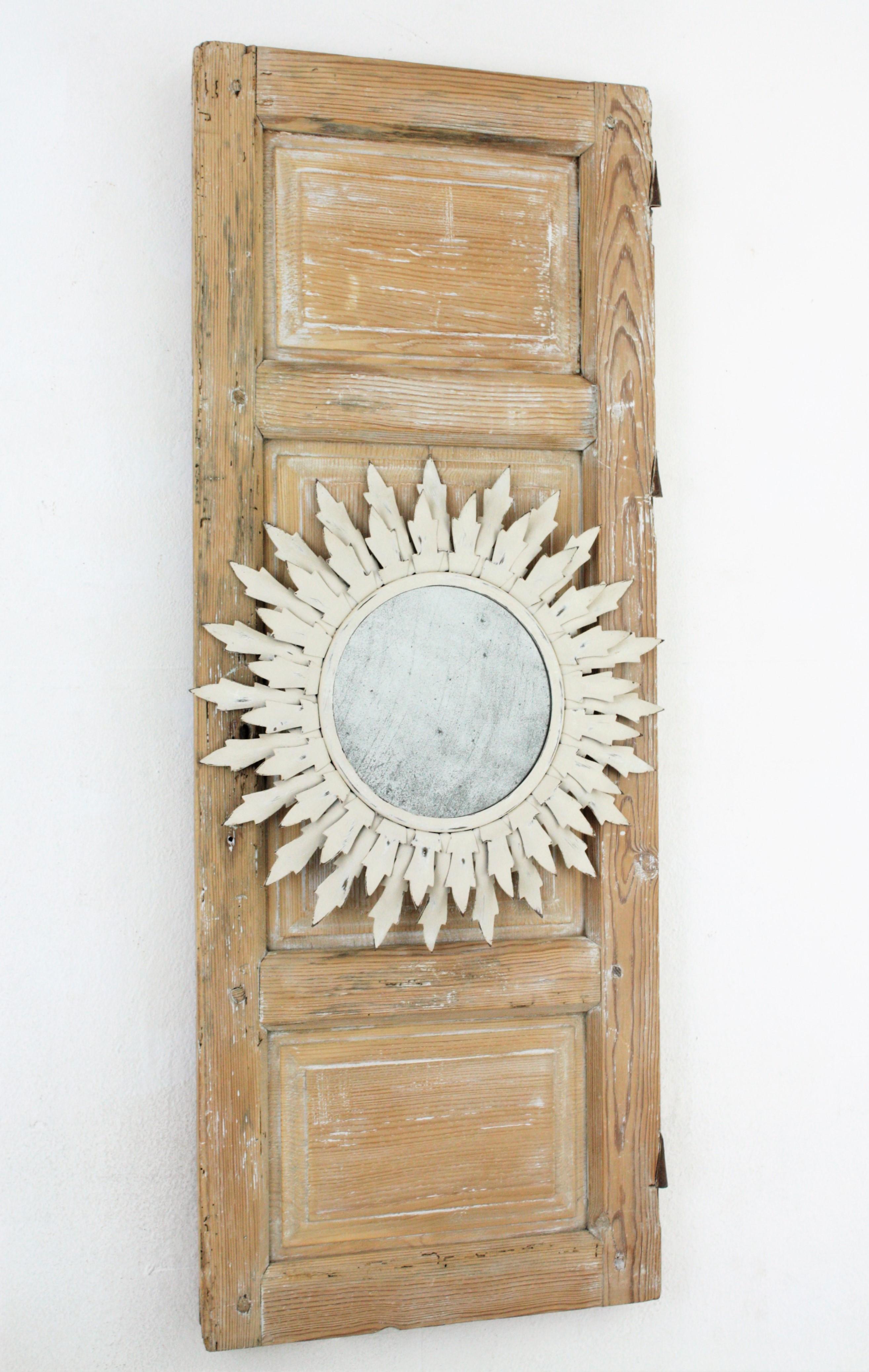 Miroir en forme de soleil à patine blanche sur une porte ancienne en bois, présenté comme un miroir Trumeau.
Ce miroir mural présente un miroir ensoleillé peint en blanc des années 1960 encadré sur une porte espagnole du XVIIIe siècle. La porte a