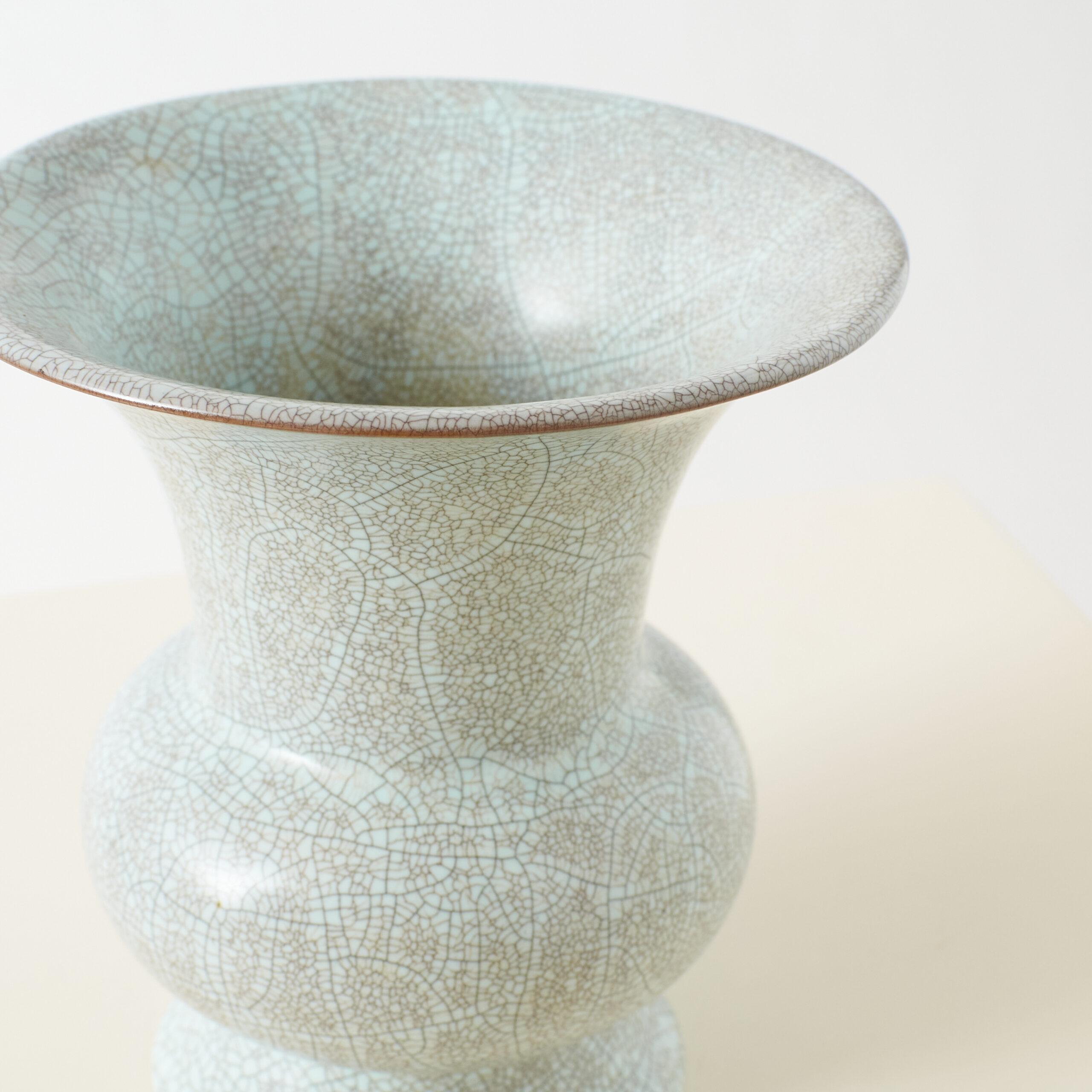 Trompetenförmige Celadon-Vase mit Crackle-Glasur

Eine chinesische Seladonvase mit einer ausladenden Trompetenform, die mit einer blassbläulich-grünen Glasur mit einem charakteristischen Ge-Crackle-Muster versehen ist, einem Markenzeichen der
