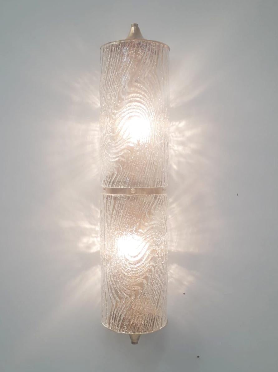 Aplique de pared o empotrable italiano con cristal de Murano transparente soplado a mano en difusores cilíndricos con motivos texturados y efecto granulado mediante la técnica Graniglia, montado en placa trasera de latón macizo con tapas decorativas