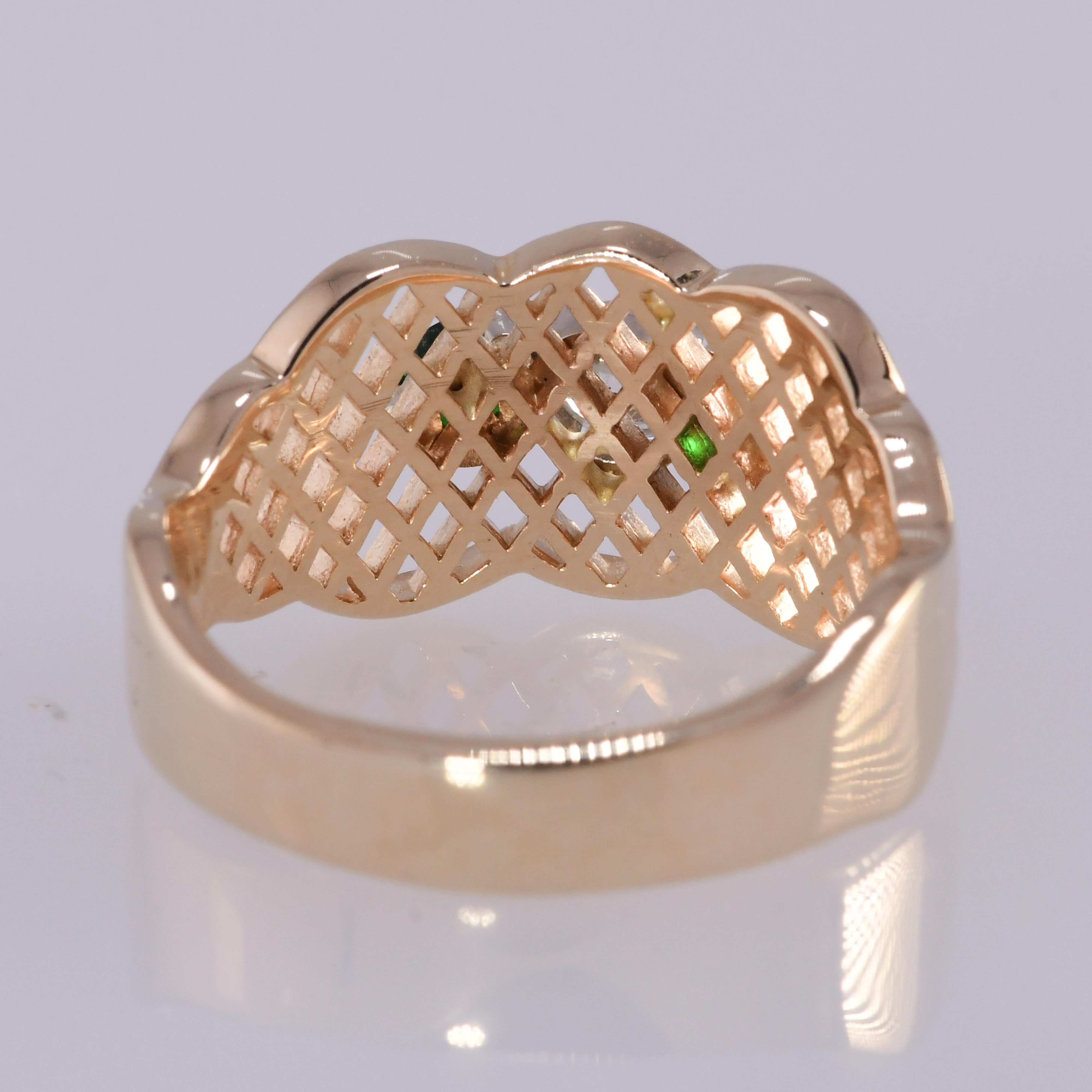 Beautiful open latticework band style ring containing .29 carat diamond and two round brilliant natural tsavorite garnets. The quality of the diamond is I1; H-I. The tsavorites have a deep vibrant green hue. The ring measures 7/8 inch wide and 7/16