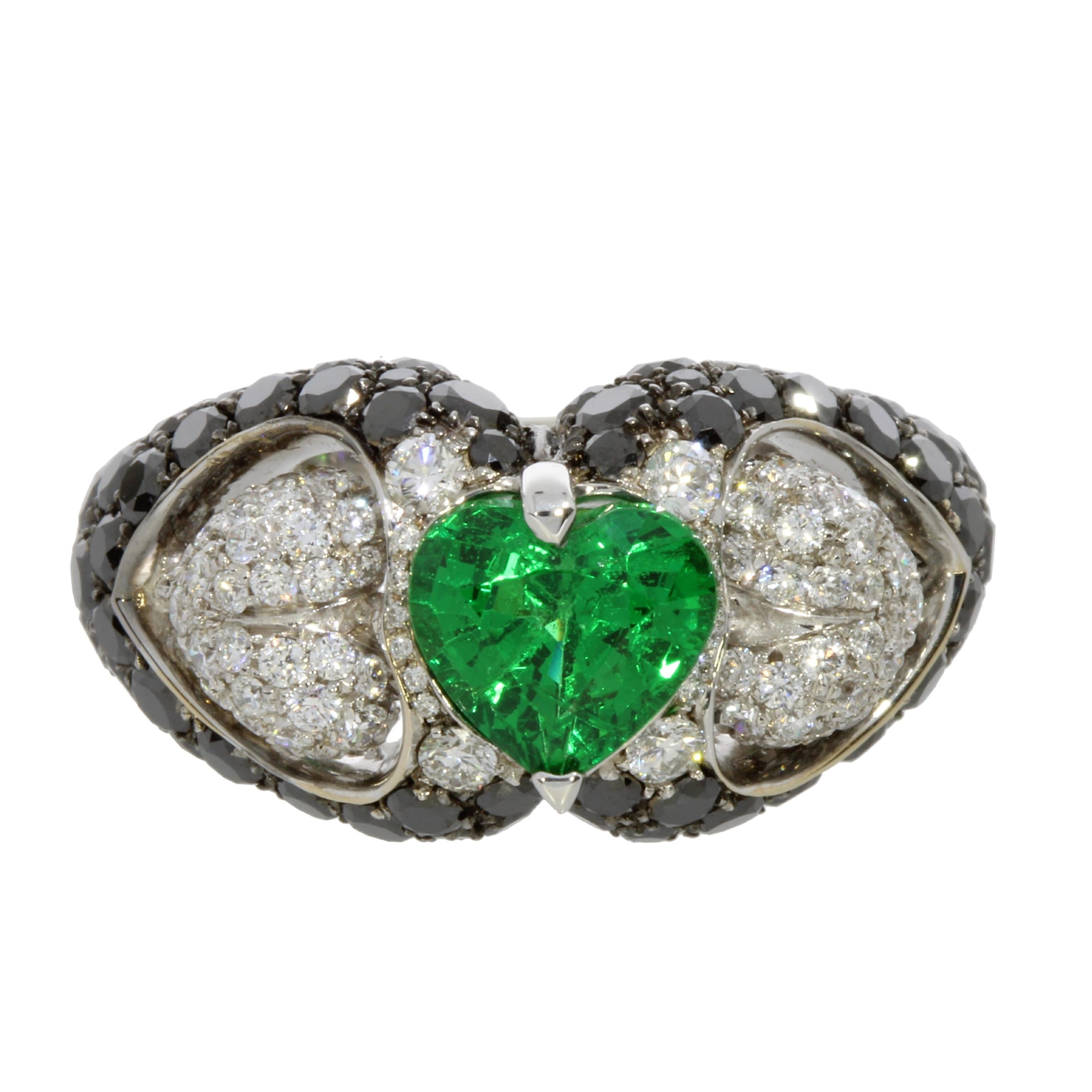 A vivid and intriguing Heart shaped Tsavorite seats between of two suspended hearts of round brilliant cut White Diamonds. The ring is completed by a glittering pave of Black Diamonds.
This ring is an original new engagement ring but is also a