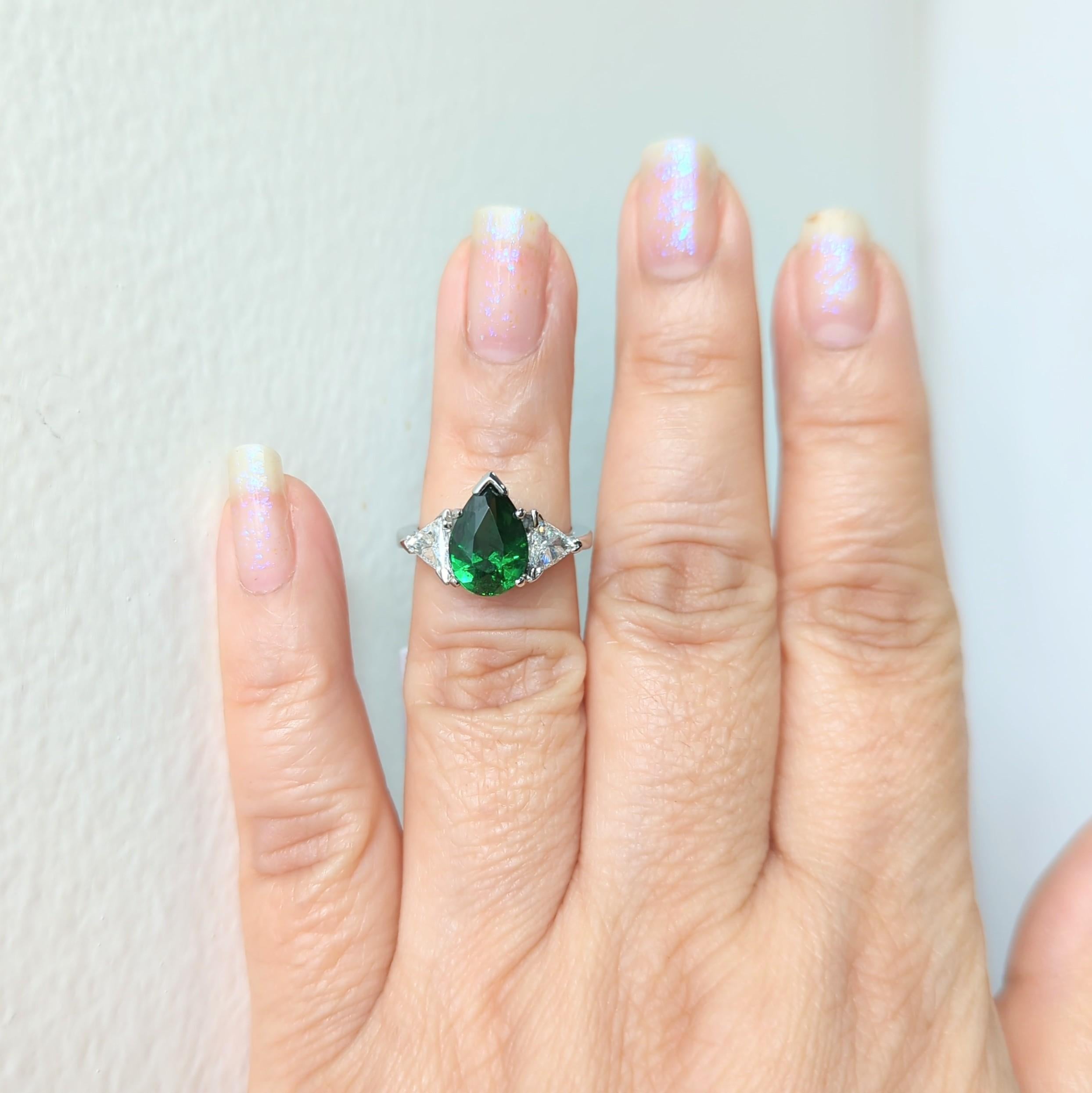Beautiful bright green 3.07 ct. tsavorite pear shape with good quality white diamond trillions on either side.  Handmade in platinum.  Ring size 6.5+.