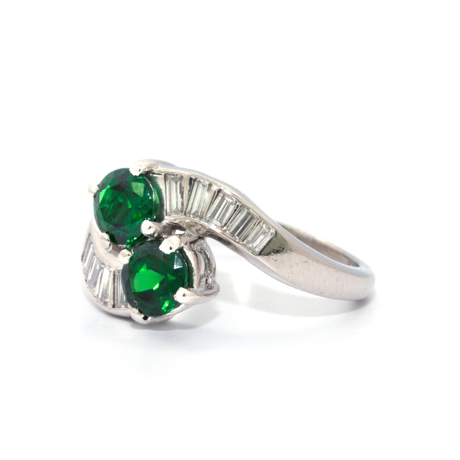 2 matching round Tsavorite Garnets with a total weight of 1.42 cts. They are accented by 10 baguette shaped diamonds that weigh 0.50cts in total. These gems are beautifully set in a stunning platinum wrap-a-round Estate ring. Size 5 3/4  6 grams    