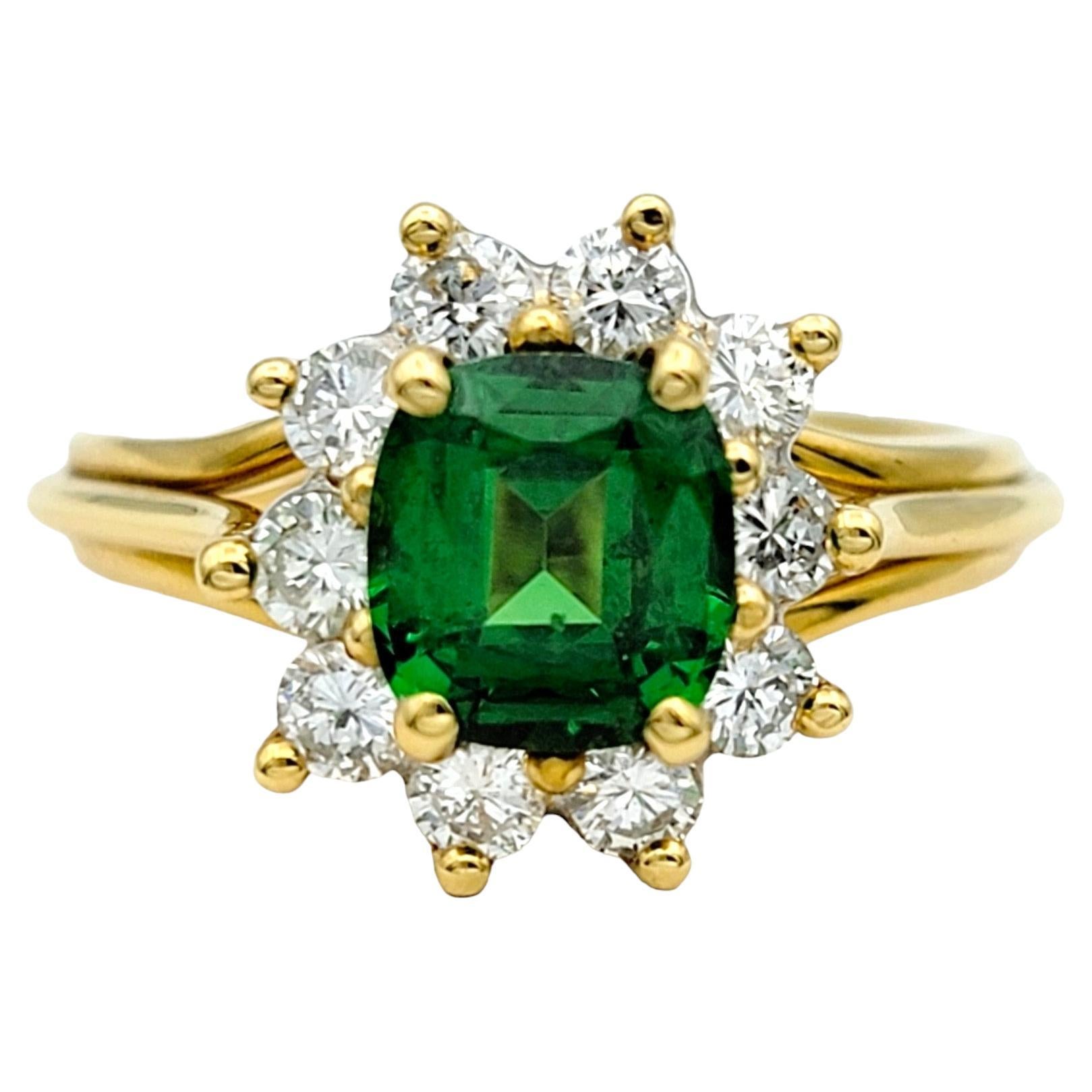 Ring Size: 6

This stunning ring showcases a vibrant green cushion-cut tsavorite gemstone, encircled by a glittering halo of diamonds, all set in warm and luxurious 18 karat yellow gold. The vivid green hue of the tsavorite is beautifully