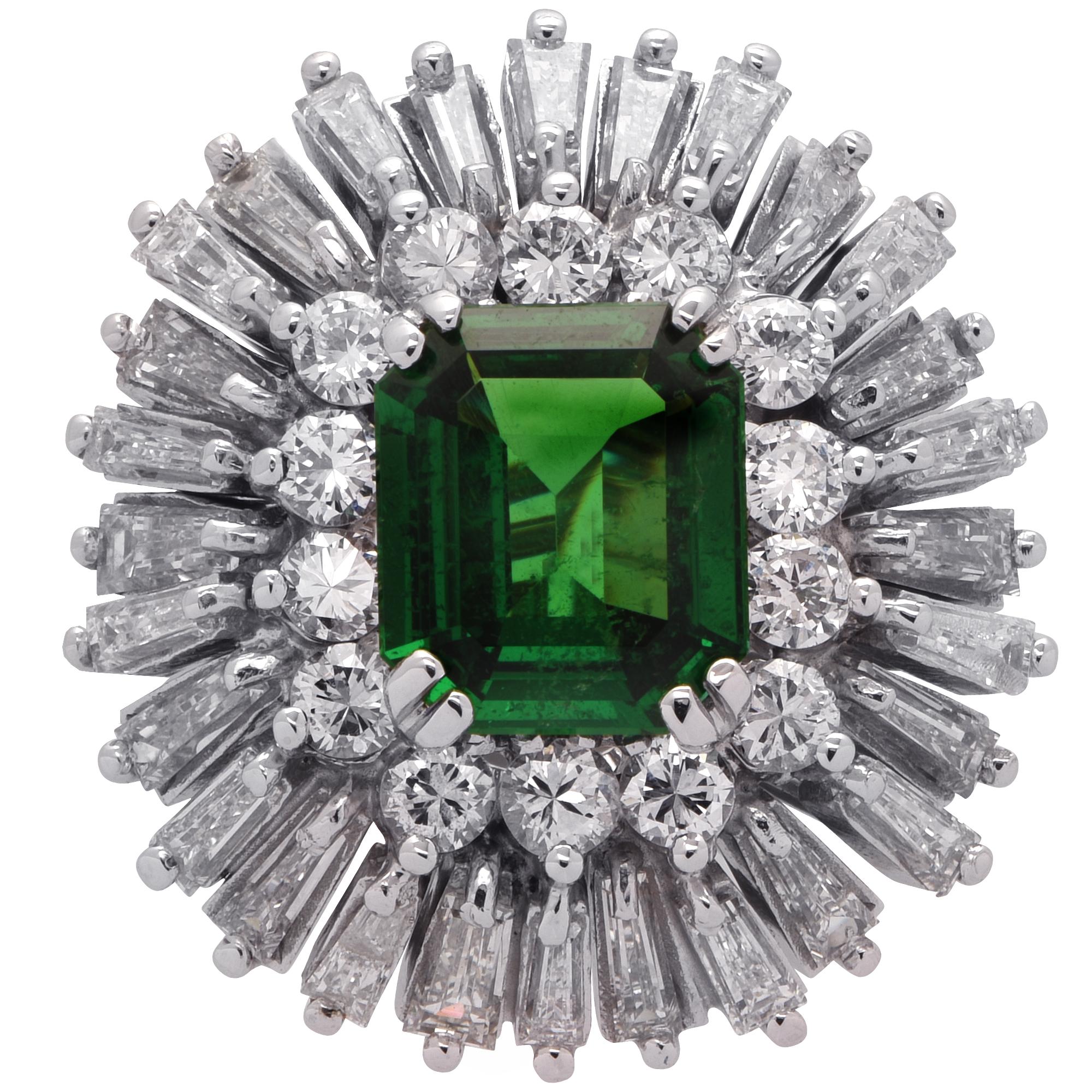Striking Tsavorite and Garnet ring crafted in 18 karat white gold, featuring an emerald cut Tsavorite Garnet weighing approximately 2.25 carats, accented by 4.17 carats of round brilliant and baguette cut diamonds, G color VS-SI clarity. The vivid
