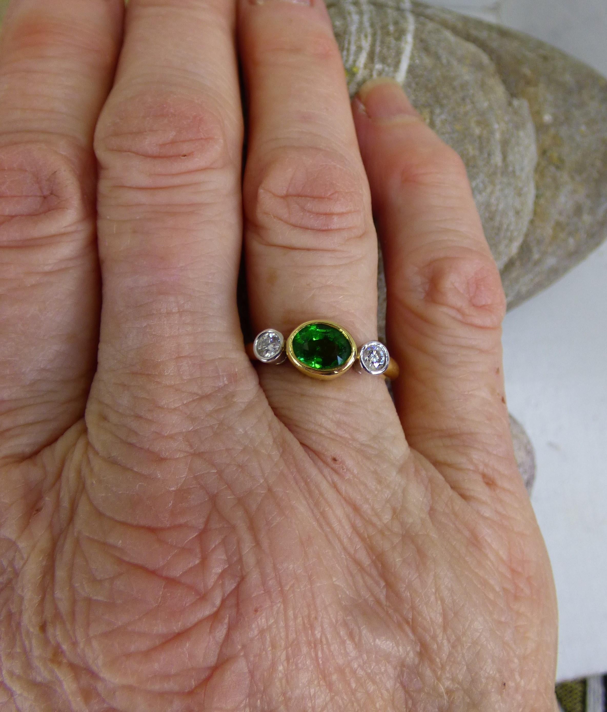 A colourful 7X5mm Tsavorite Garnet weighing 1.42ct is set between two Diamonds with a total Diamond weight of .18ct.  The ring is handmade in 18K yellow gold with the Diamonds set in 18K white gold. The ring is hallmarked by the Dublin Assay Office.
