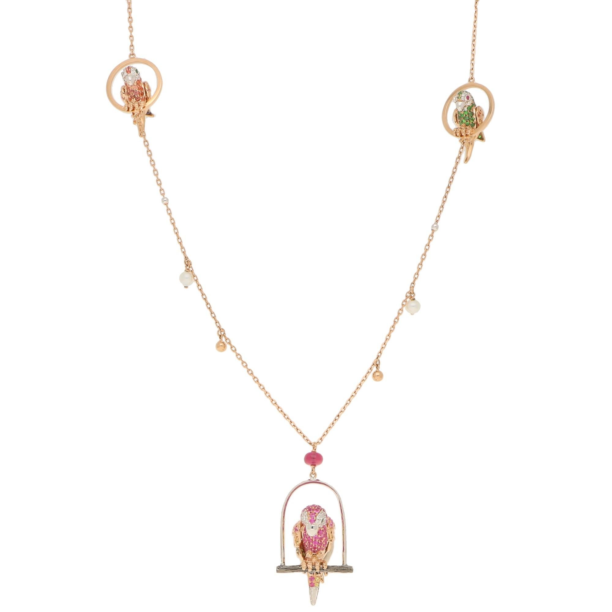 A pretty and unusual parrot necklet set on 18ct rose and white gold. The main feature parrot is perched on a white gold swing roost and is grain set with round blue, pink and yellow sapphires, tsavorite garnets and diamonds across its body, wings