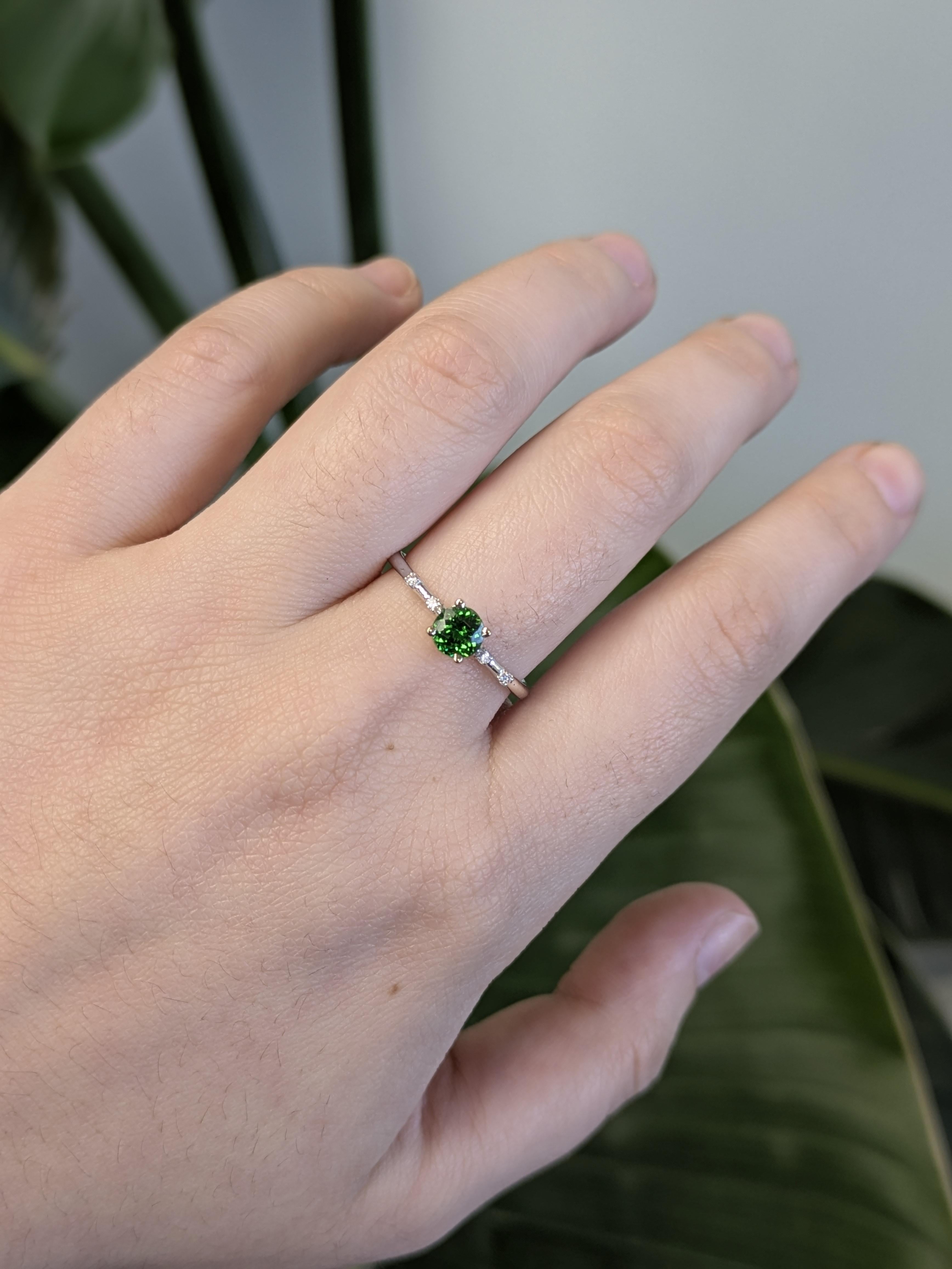 Cette éblouissante bague en grenat tsavorite est ornée d'une pierre précieuse de taille ronde d'un vert éclatant, rehaussée de diamants naturels étincelants pour une touche raffinée. Fabriquée en or blanc massif 14k, cette pièce élégante respire le