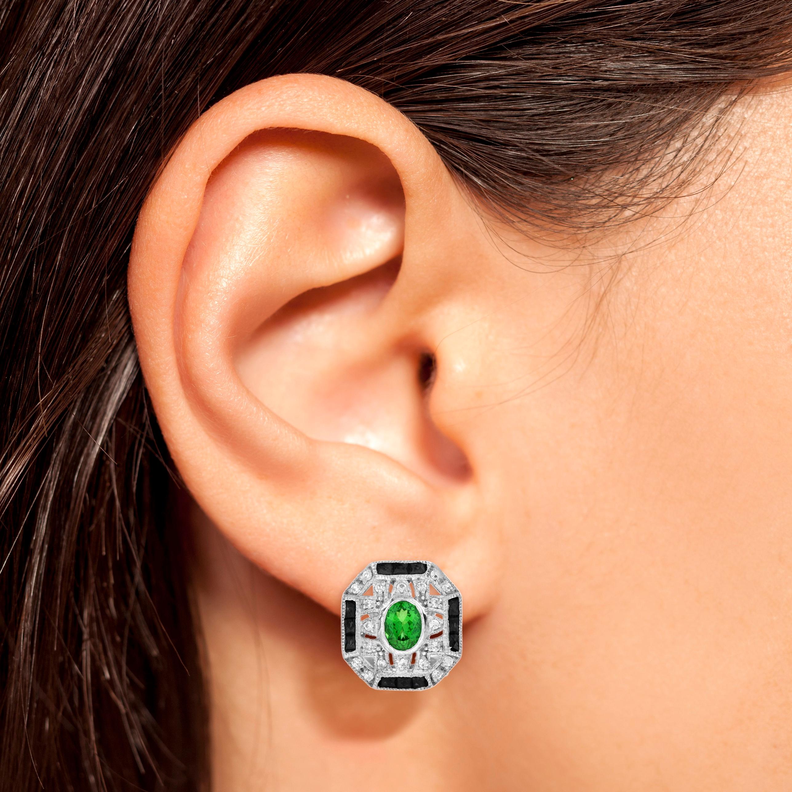 These stunning Tsavorite, Onyx, and Diamond Art Deco Style Omega Earrings in 14K White Gold effortlessly blend timeless elegance with modern sophistication. The vibrant green Tsavorite garnets are artfully set against the striking contrast of bold