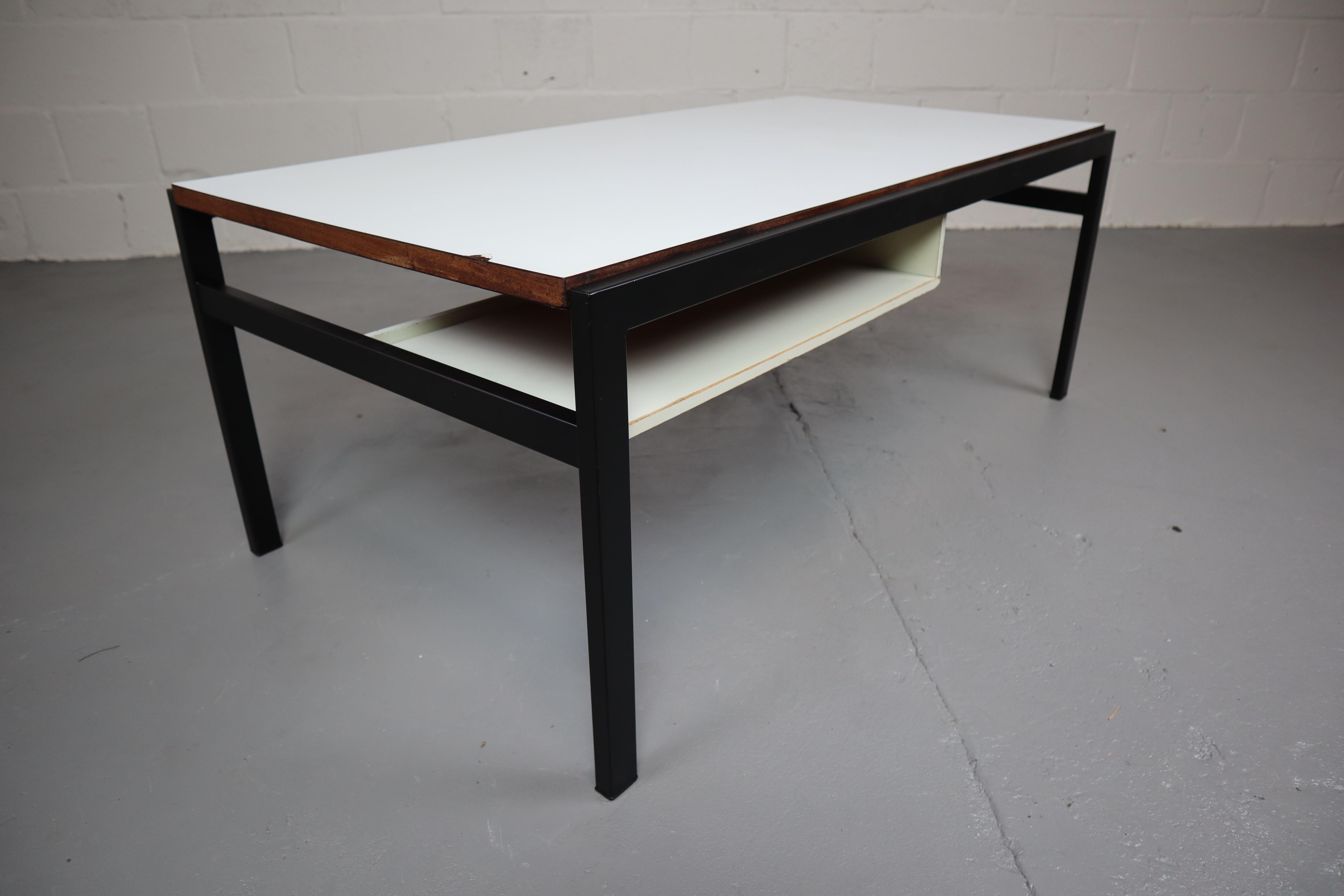 Couchtisch TU04, entworfen von Cees Braakman für Pastoe in den 1950er Jahren.
Dieser Tisch hat eine wendbare Tischplatte (Teakholz- oder Formica-Seite), schwarze Metallbeine und einen schwimmenden Zeitschriftenhalter unter der Tischplatte.
Der Tisch