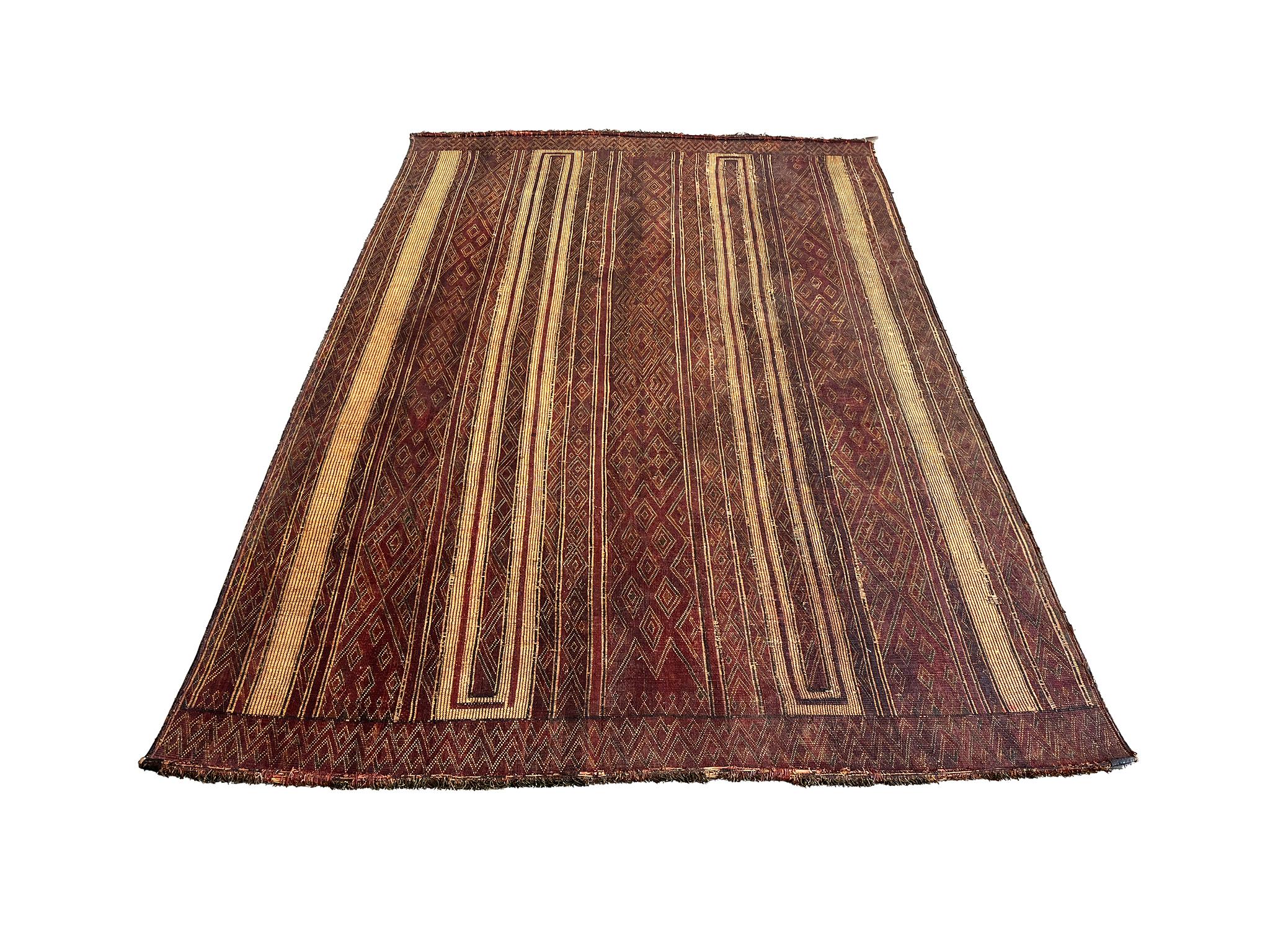 20th Century Tuareg woven rug made of leather and reed. The design consists of diamond and linear patterns in an earthy palette of browns, dark reds, black, and straw yellow.

Dimensions:
132 in. x 88 in. (11' x 7' 4