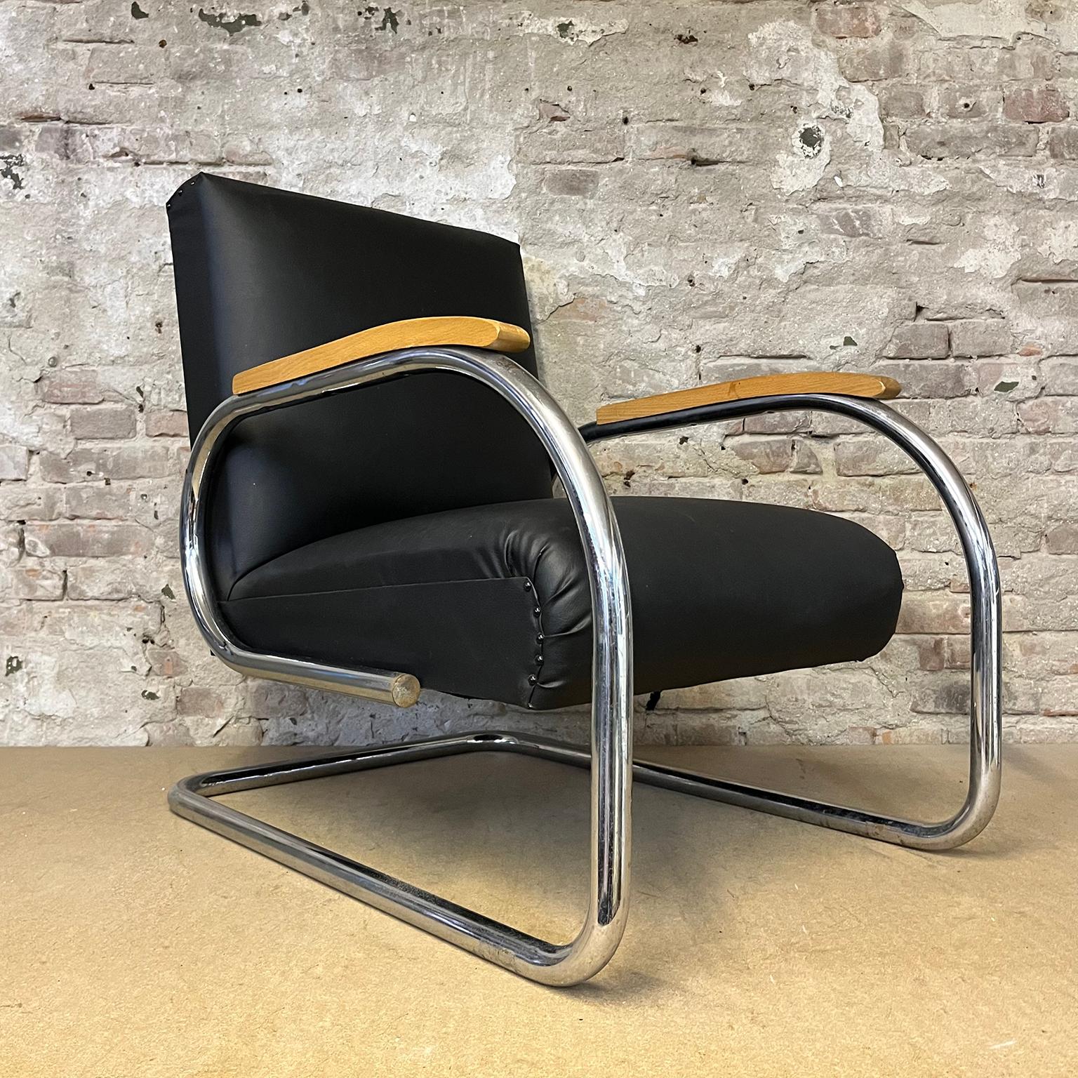 Easy Chair, from a Flemish designer in Black leathered with natural wooden armrests. The Armchair show some signs of use like some spots on the upholstery and the base as well as some scratches on the Wooden armrests. The metal cover caps show some