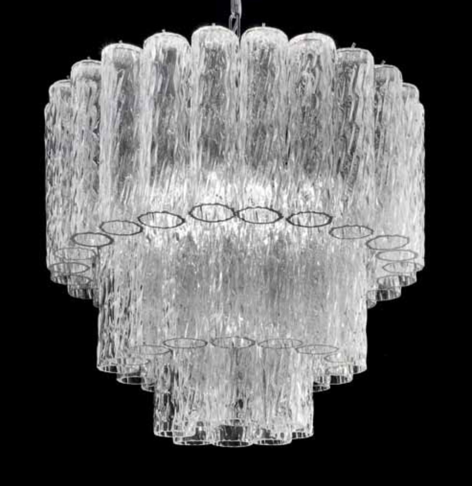 Lampadario italiano con tubi in vetro di Murano chiaro e testurizzato disposti su più livelli, montati su una struttura in metallo con finitura cromata / Made in Italy
6 luci, tipo E26 o E27, max 60W ciascuna e 1 luce, tipo E12 o E14, max