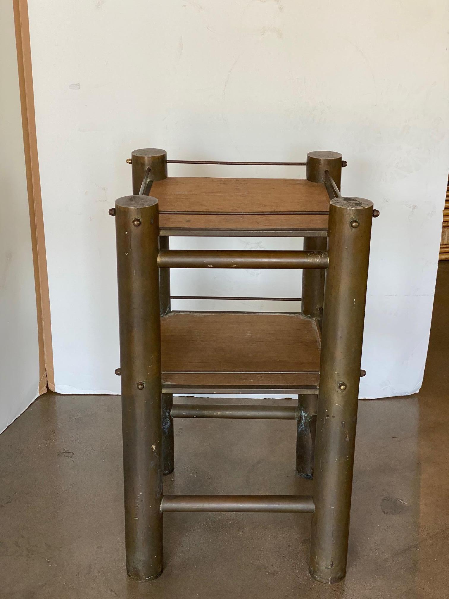 Ein Beistelltisch oder ein Regal, das aus schwerem Messingrohr gefertigt ist.  Der doppelstöckige Rahmen ist unlackiert und hat eine warme Patina, da er zwei eingelassene Holzböden trägt.