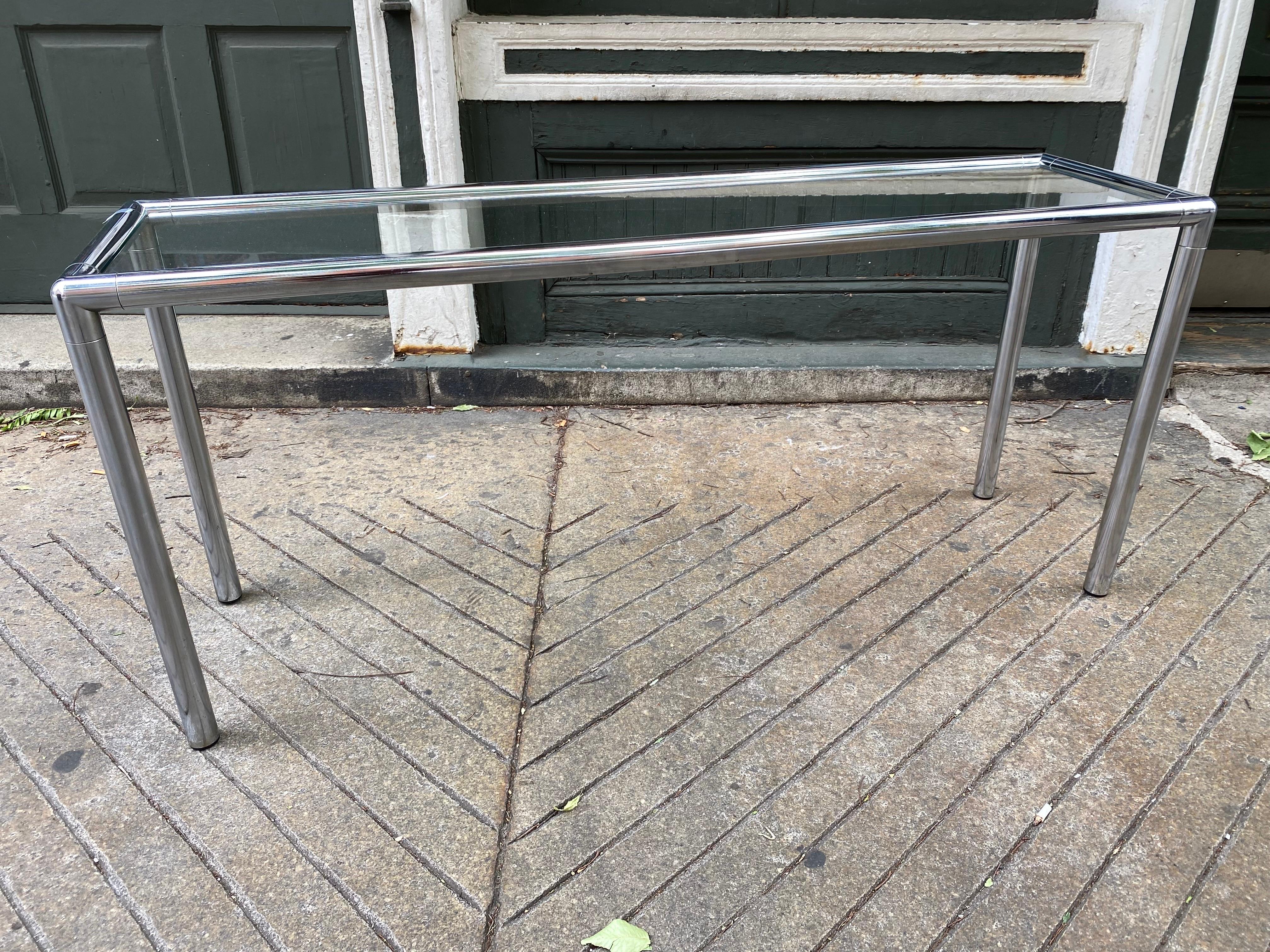 Table de canapé en chrome tubulaire avec plateau en verre légèrement encastré. Belle échelle, parfaite pour être utilisée avec un canapé ou devant une fenêtre ! Le chrome est assez propre, une jambe présente quelques piqûres à l'arrière. Dans