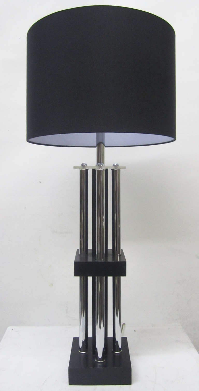 This two-tiered table lamp features a wooden structure reinforced by four chrome tubular columns. The base and middle tier of the lamp are black woodblocks, and the body is topped off with a Lucite square. The height without the black linen shade is