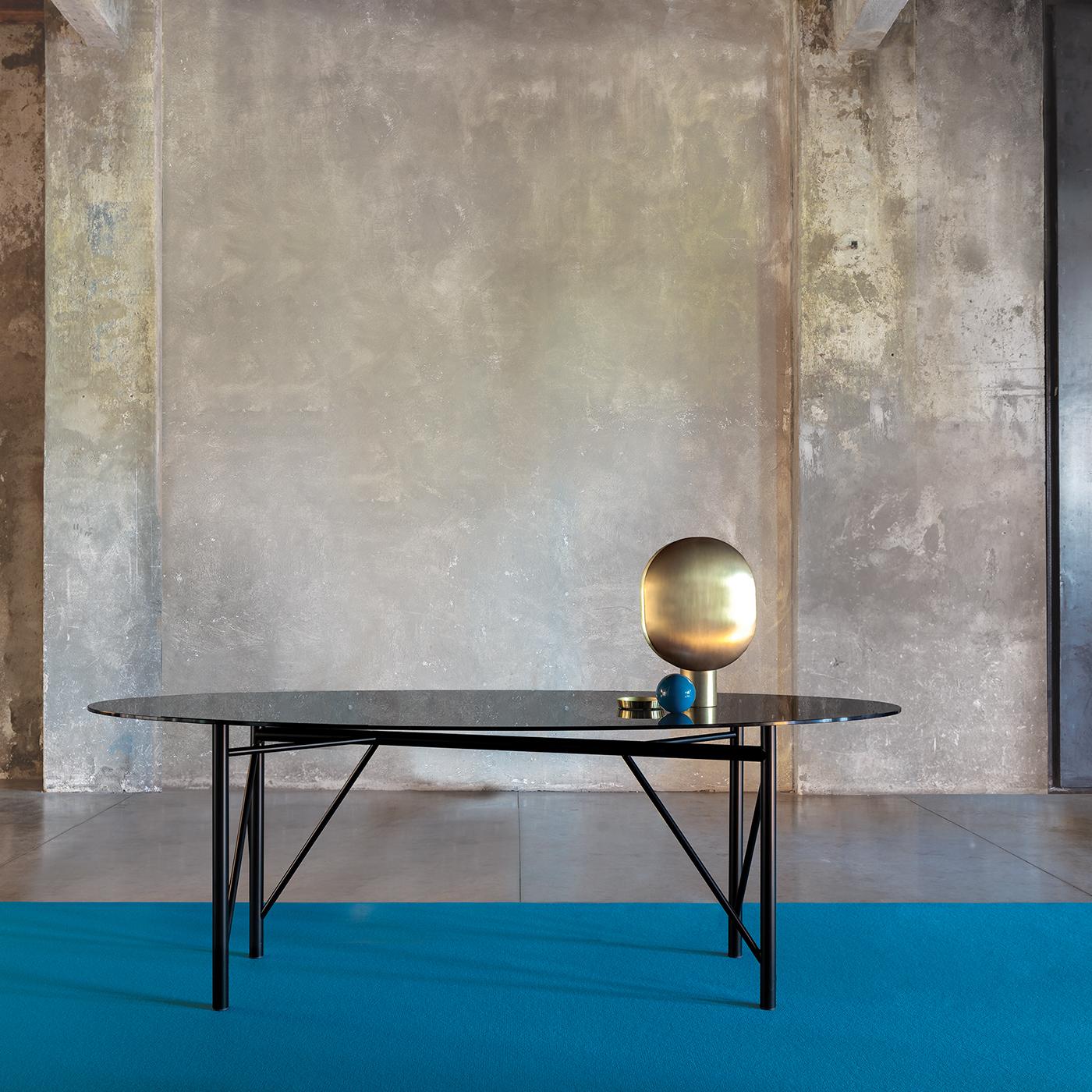 On a refined metal base in a black powder coated finish, the Tubular oval dining table is topped with a gray glass top that allows the base to take center stage. The epitome of contemporary cool, the table is designed for minimalist spaces. The