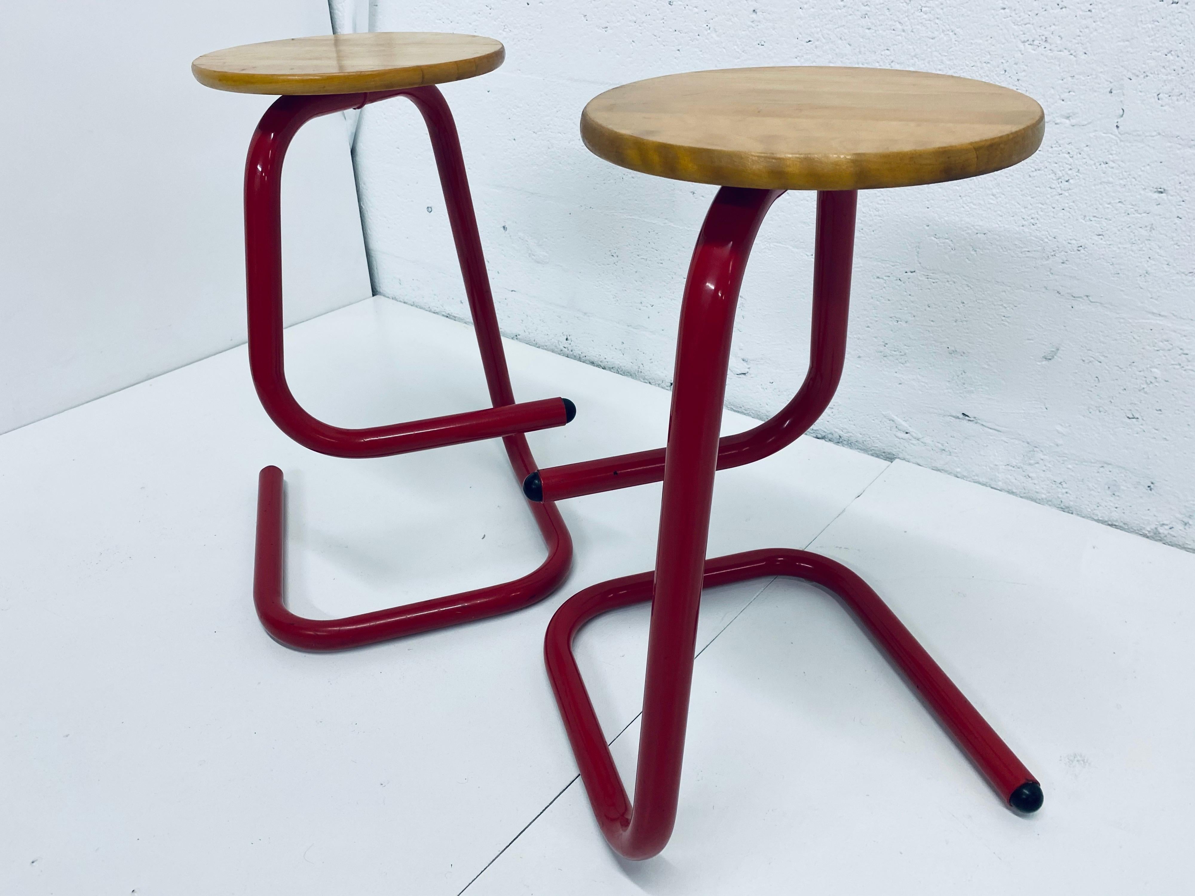 Red lacquered tubular steel frame with natural wood seat paperclip stools by Les Industries Amisco.