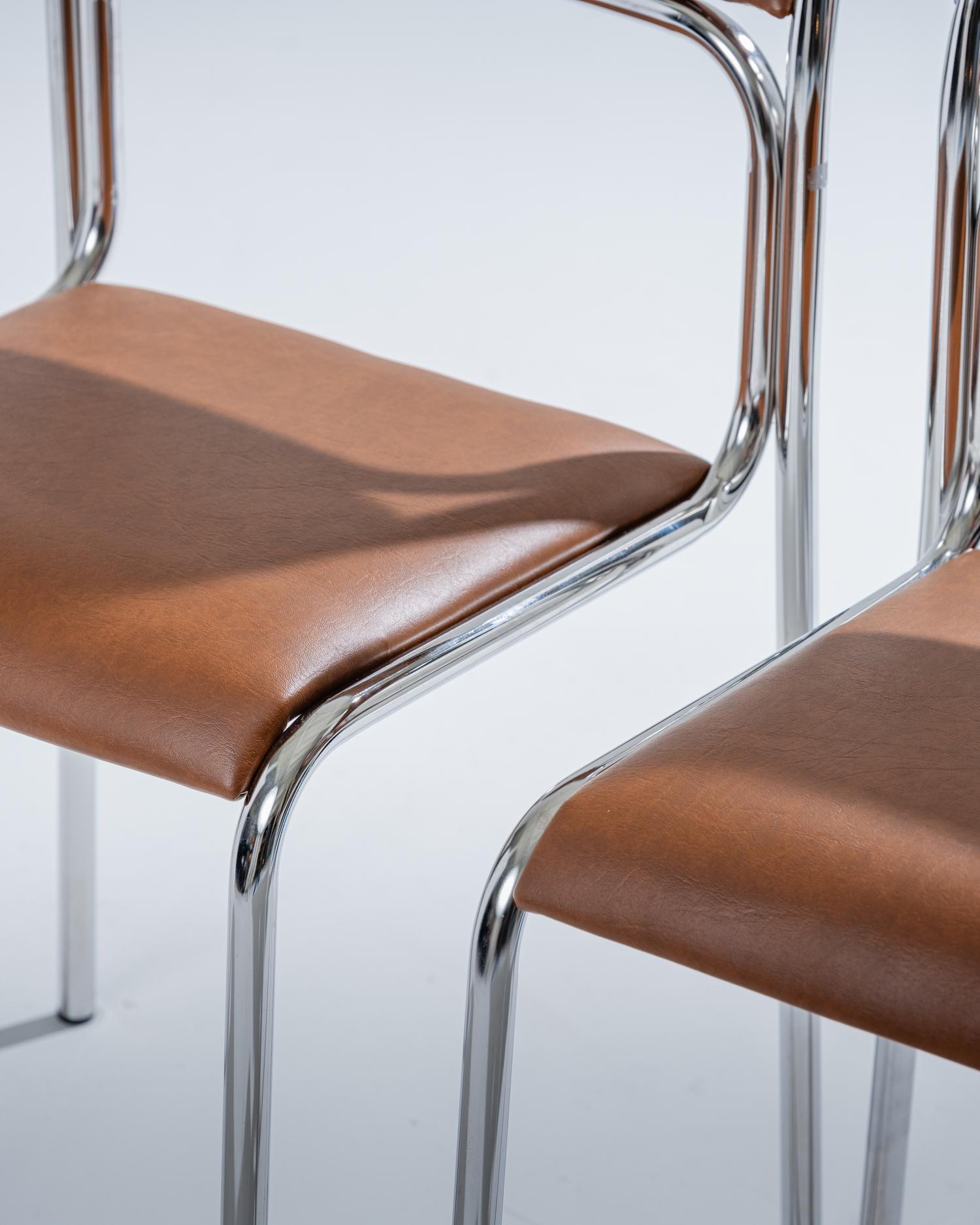 Chaise au design inspiré du mouvement Bauhaus, fabriquée dans les années 1980. Structure tubulaire en acier chromé, associée à une assise et un dossier en simili cuir cognac. Elle est en excellent état.