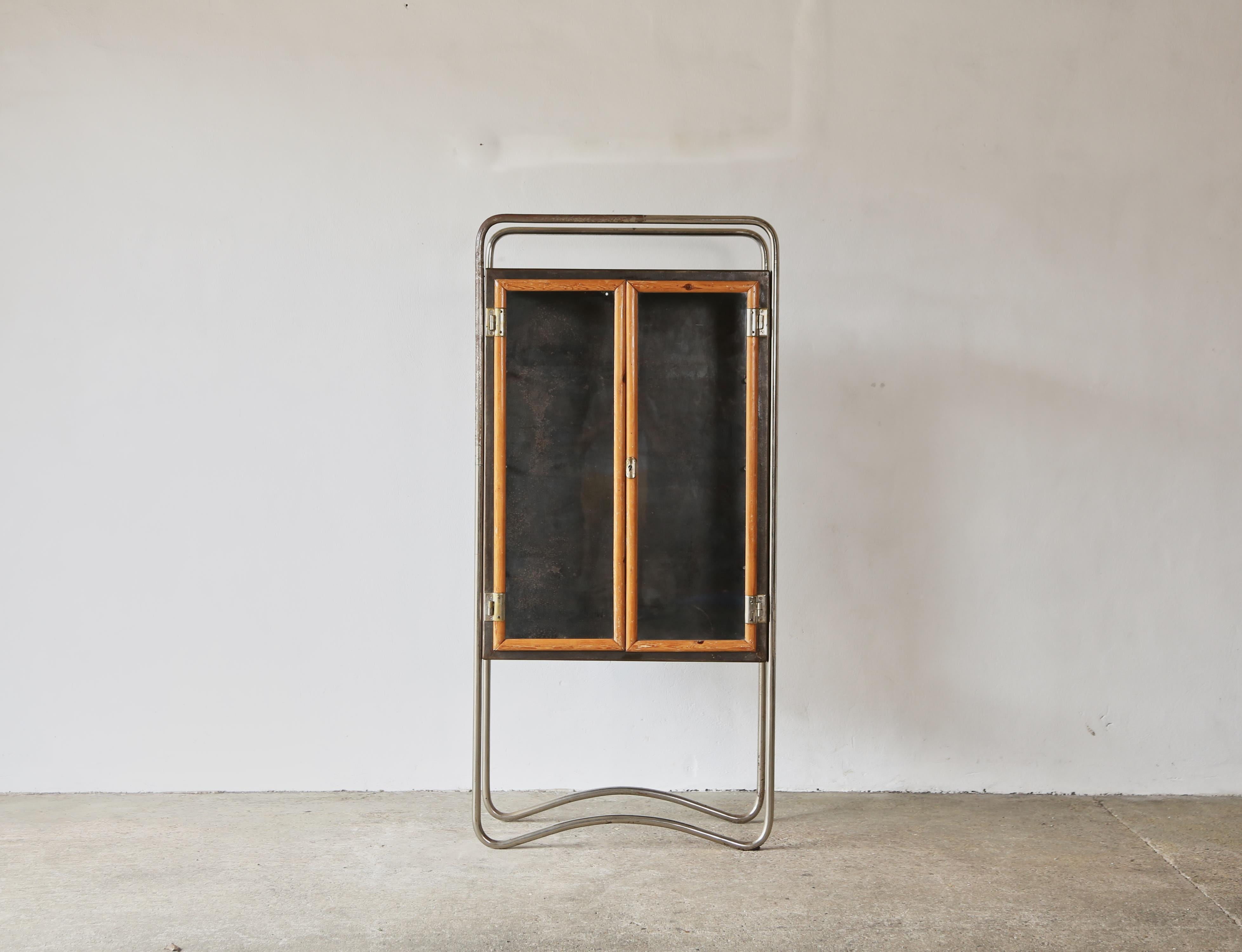 Tubular steel, wood and glass cabinet, 1940s.   Original key present.   The removable glass side panels and glass shelves have been replaced.  Some wear to tubular steel frame (as photographed).   Fast shipping worldwide.




