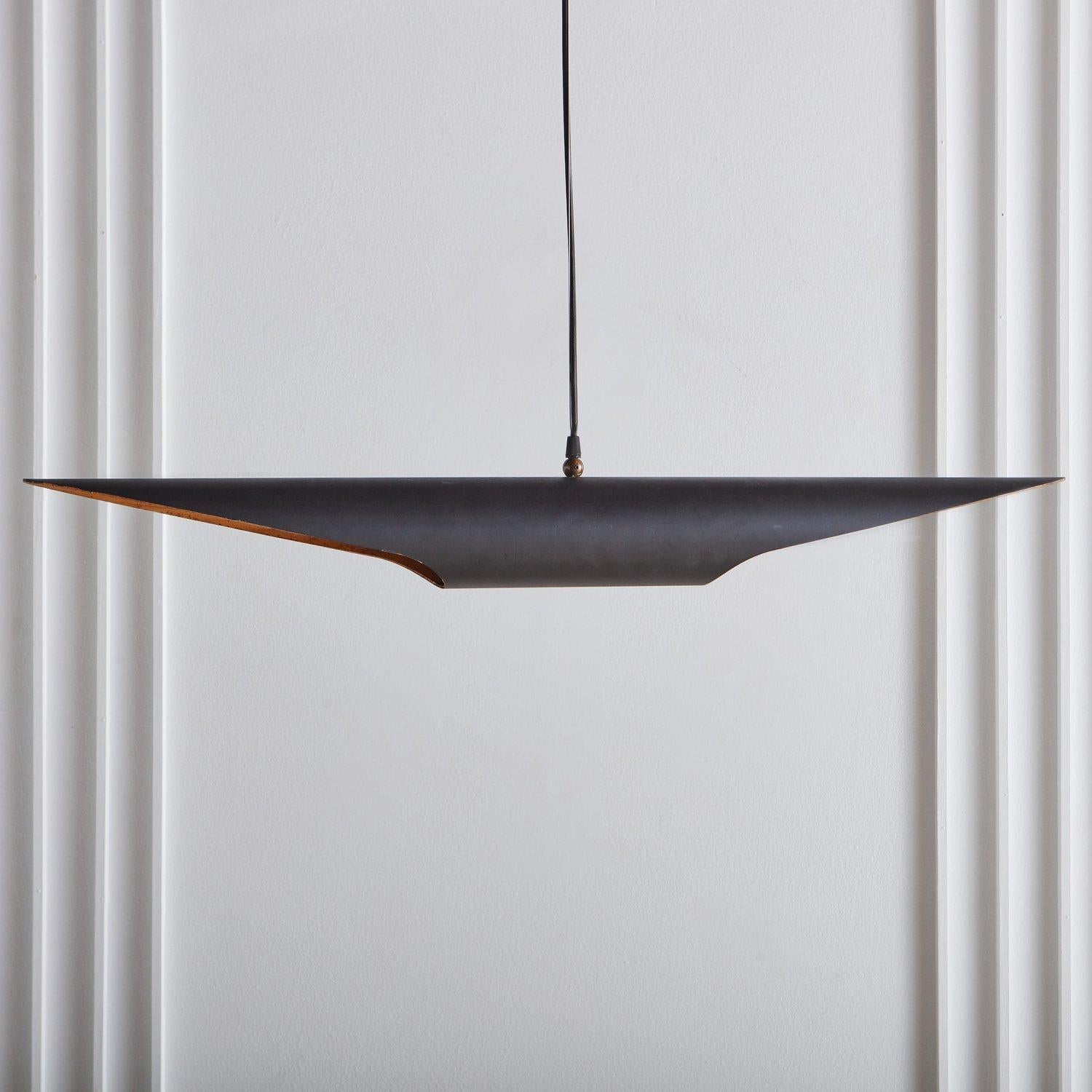 A striking vintage Italian pendant light featuring an elongated steel tubular body which was powder coated matte black and has sharply angled edges. It has a gorgeous hand applied gold leaf interior and hangs from a black cord with a new black