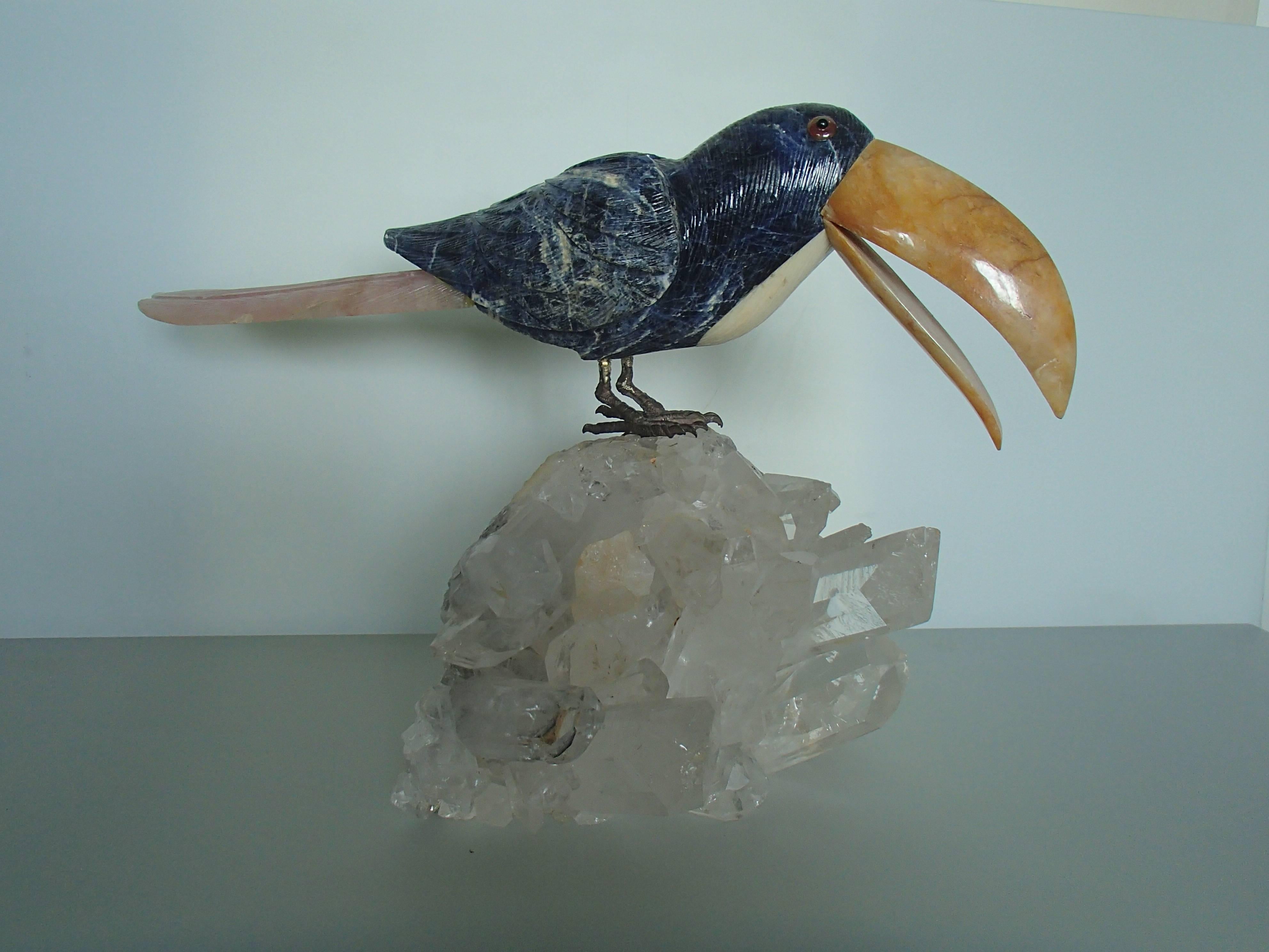 Tucan sitting on a crystall made of sodalith and rose quarz.
