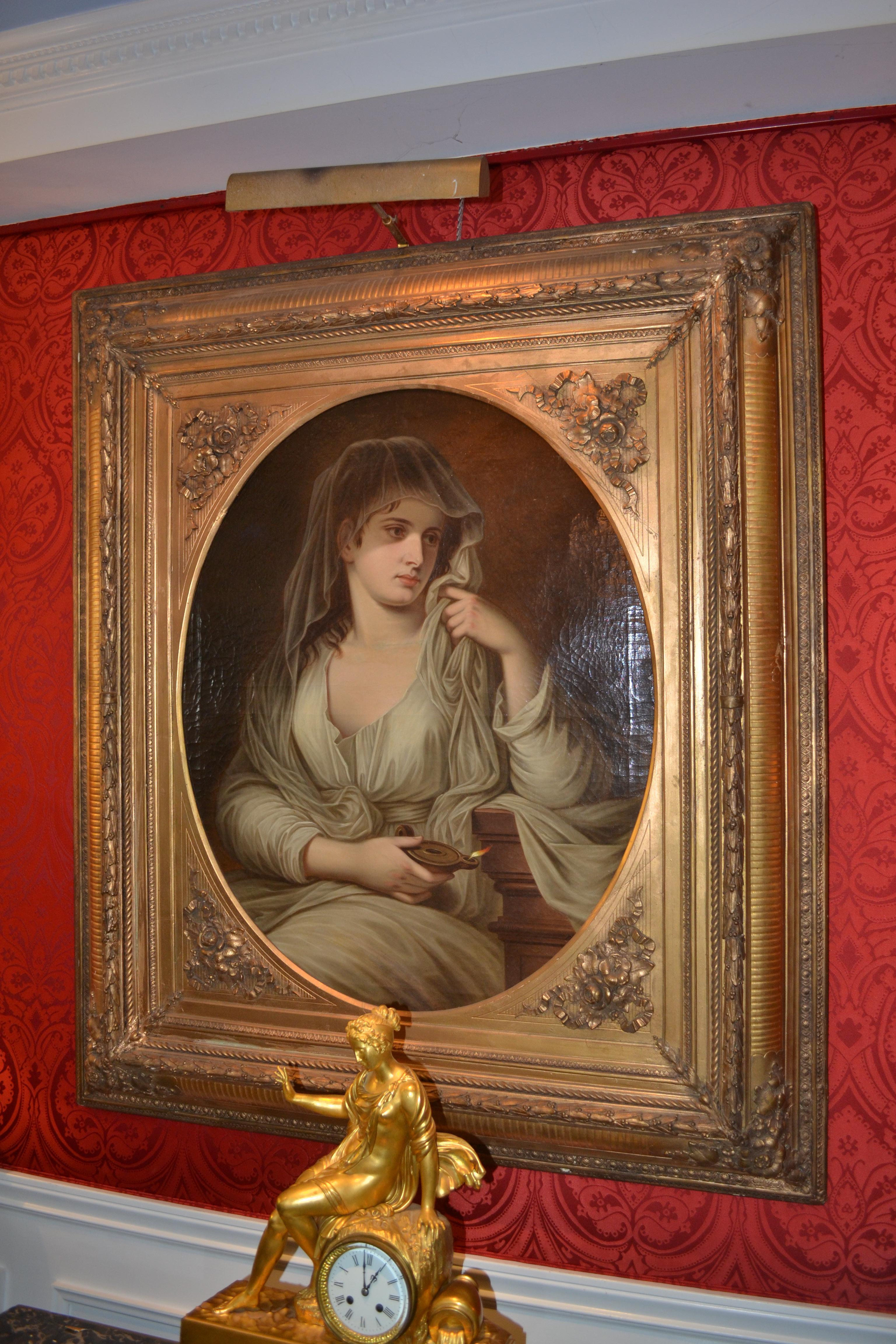 An oil painting on canvas showing a portrait of a  classical maiden depicted as a vestal virgin dressed in classical attire, having chestnut hair concealed by a guarnello or thin veil and holding a Roman oil lamp.

The painting signed “F. Hofelder