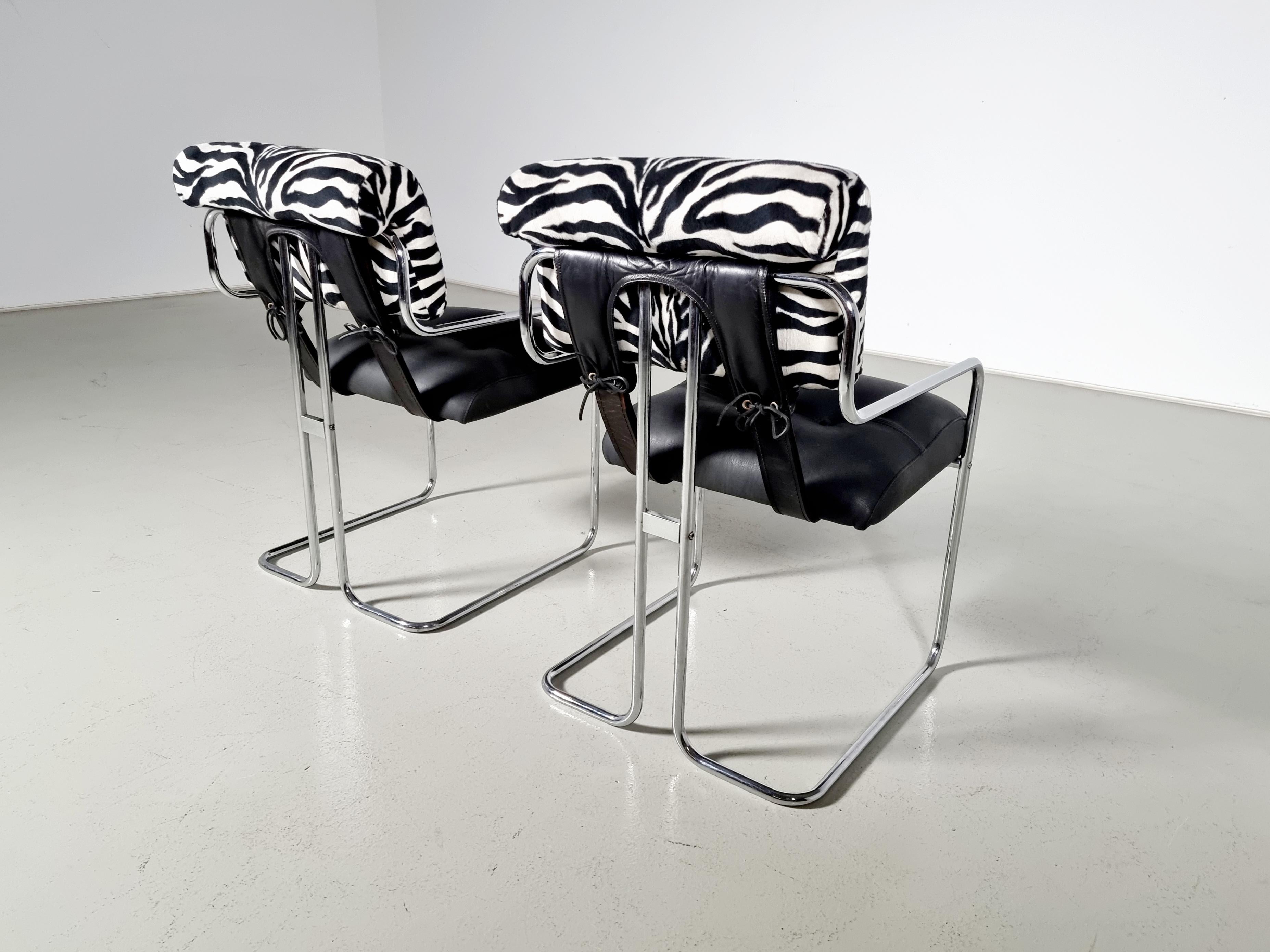 Set of 2 black leather, zebra fabric, and chrome chairs designed by Guido Faleschini for Mariani, Pace collection. The leather and fabric upholstery is attached to graceful polished steel tubular frames, as well as is bridged together by leather