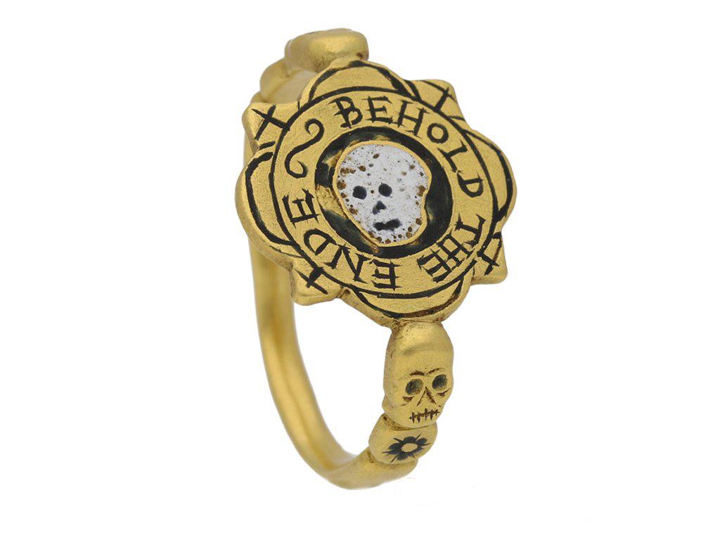 Tudor enameled 'BEHOLD THE ENDE' skull ring. Formed to centre with a irregular quartefoil bezel, featuring a horizontal white and black enameled skull encased in a circular black enameled background, surrounded by the inscription 'BEHOLD THE ENDE'