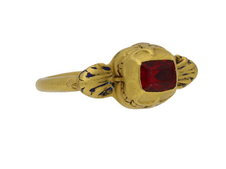 Tudor gold spinel set ring. Set to centre with a rectangular table cut red spinel in a closed back rubover setting with an approximate weight of 1.00 carats, to a raised rectangular bezel with intricately scalloped decoration, the shoulders richly