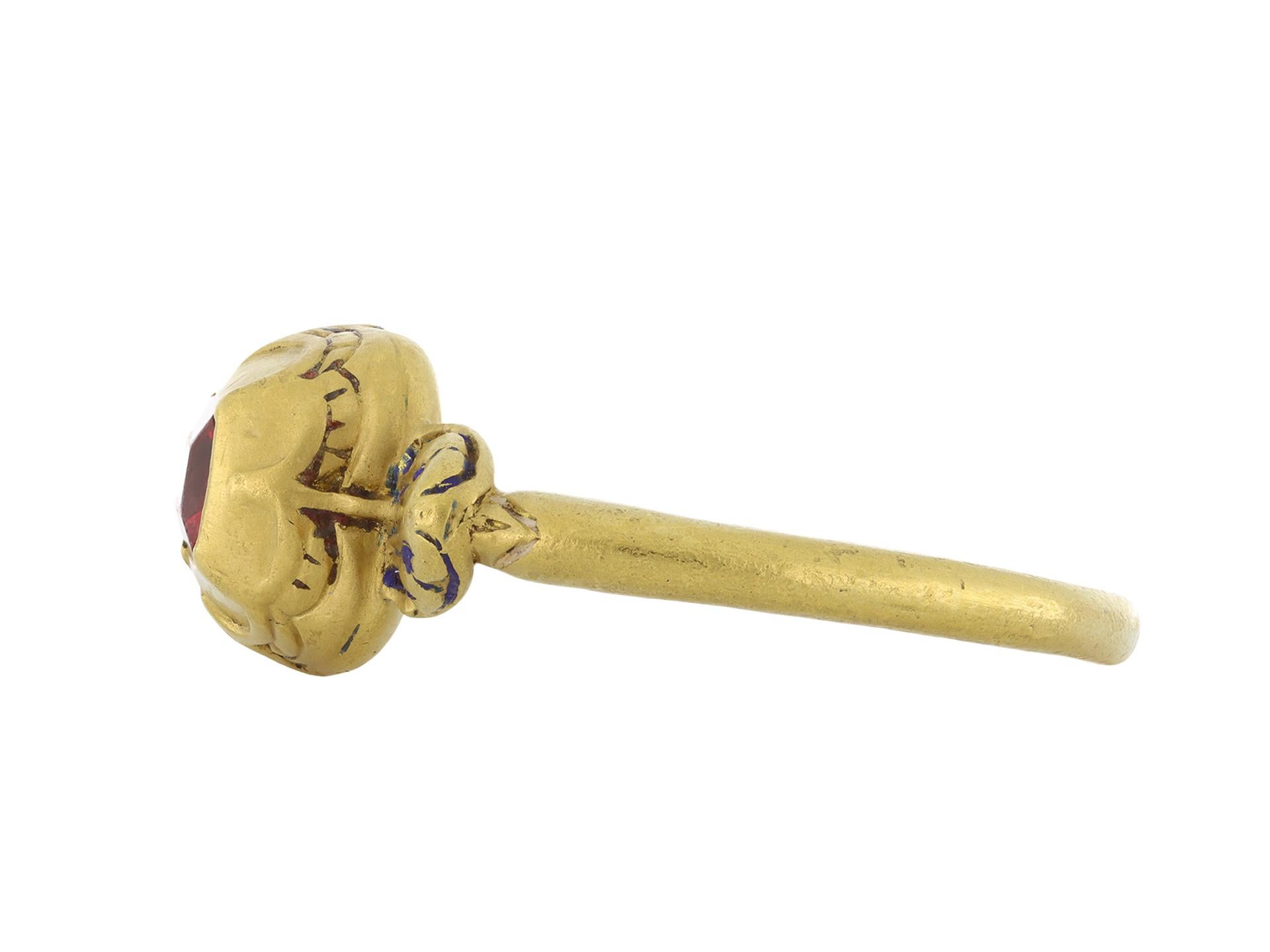 Ring aus Tudor-Gold mit Spinellbesatz. In der Mitte befindet sich ein rechteckiger roter Spinell im Tafelschliff in einer geschlossenen Fassung mit einem Gewicht von etwa 1,00 Karat. Die Schultern sind reich mit Muschelmotiven beschnitzt und zeigen
