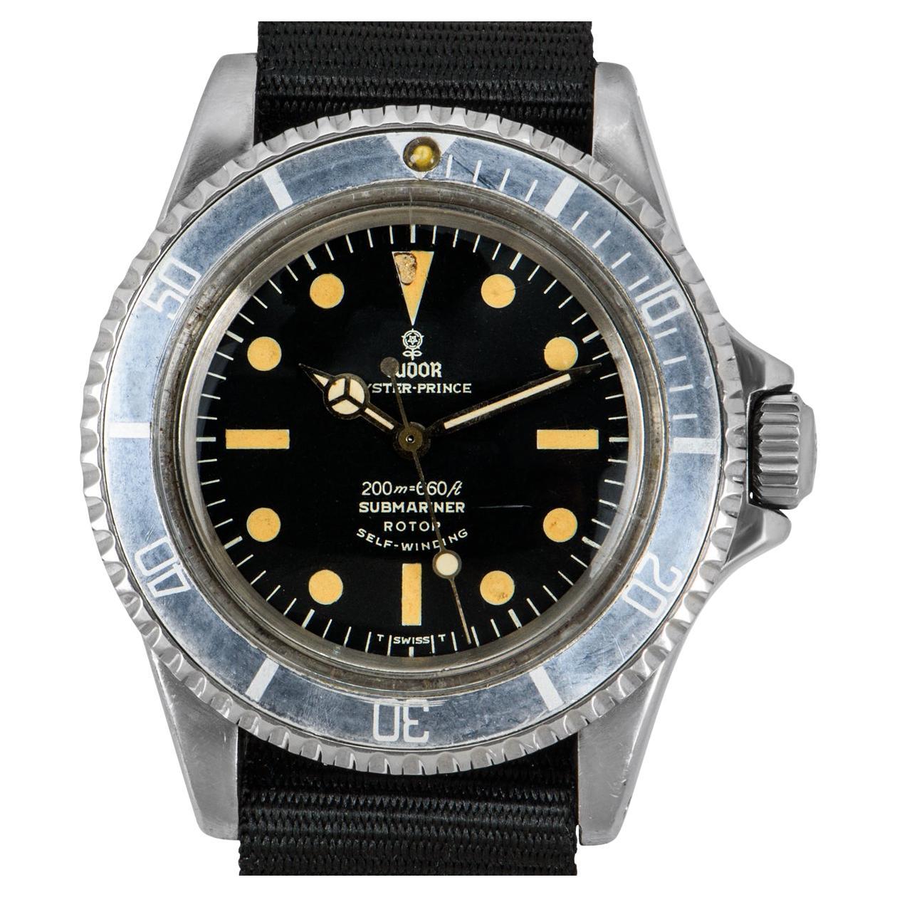 Une Submariner vintage en acier inoxydable de 40 mm de Tudor. Dotée d'un cadran noir mat et d'une lunette tournante bidirectionnelle en acier inoxydable avec insert noir. Équipé d'une sangle noire de style nato et d'une boucle à ardillon générique.