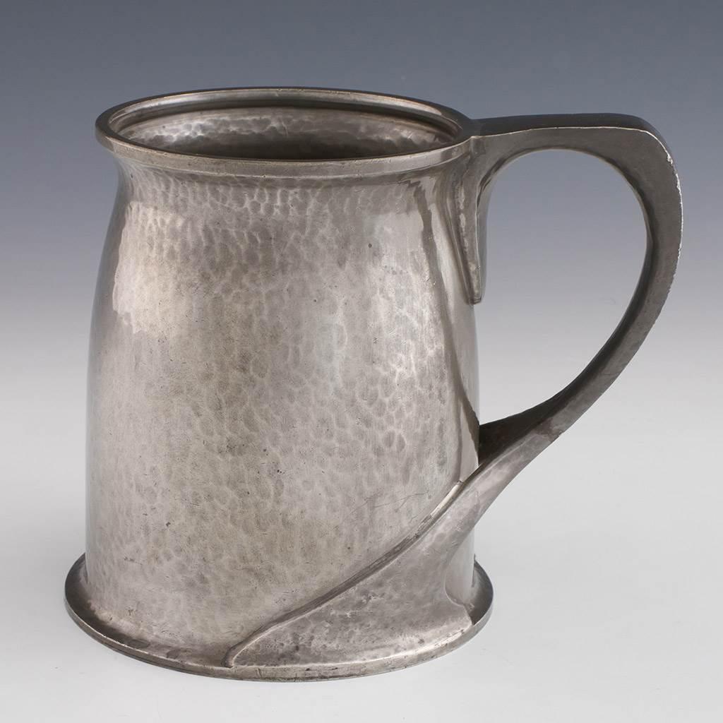 Heading : Tudric for Liberty pewter tankard
Date : Designed by Oliver Baker in 1902
Period : Edward VII
Origin : England
Decoration : Applied naturalistic handle. Marked Tudric English Pewter Liberty & Co 066 to base
Size :  Height 12.5cm. base