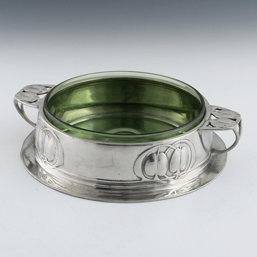 Titolo : Burriera Tudric in peltro con rivestimento in vetro
Data: c1905
Periodo: Edoardo VII
Origine : Inghilterra
Decorazione: decorazione classica Tudric Arts and Crafts con frutta fusa sui lati e sui manici. Fodera in vetro verde. Peltro inglese