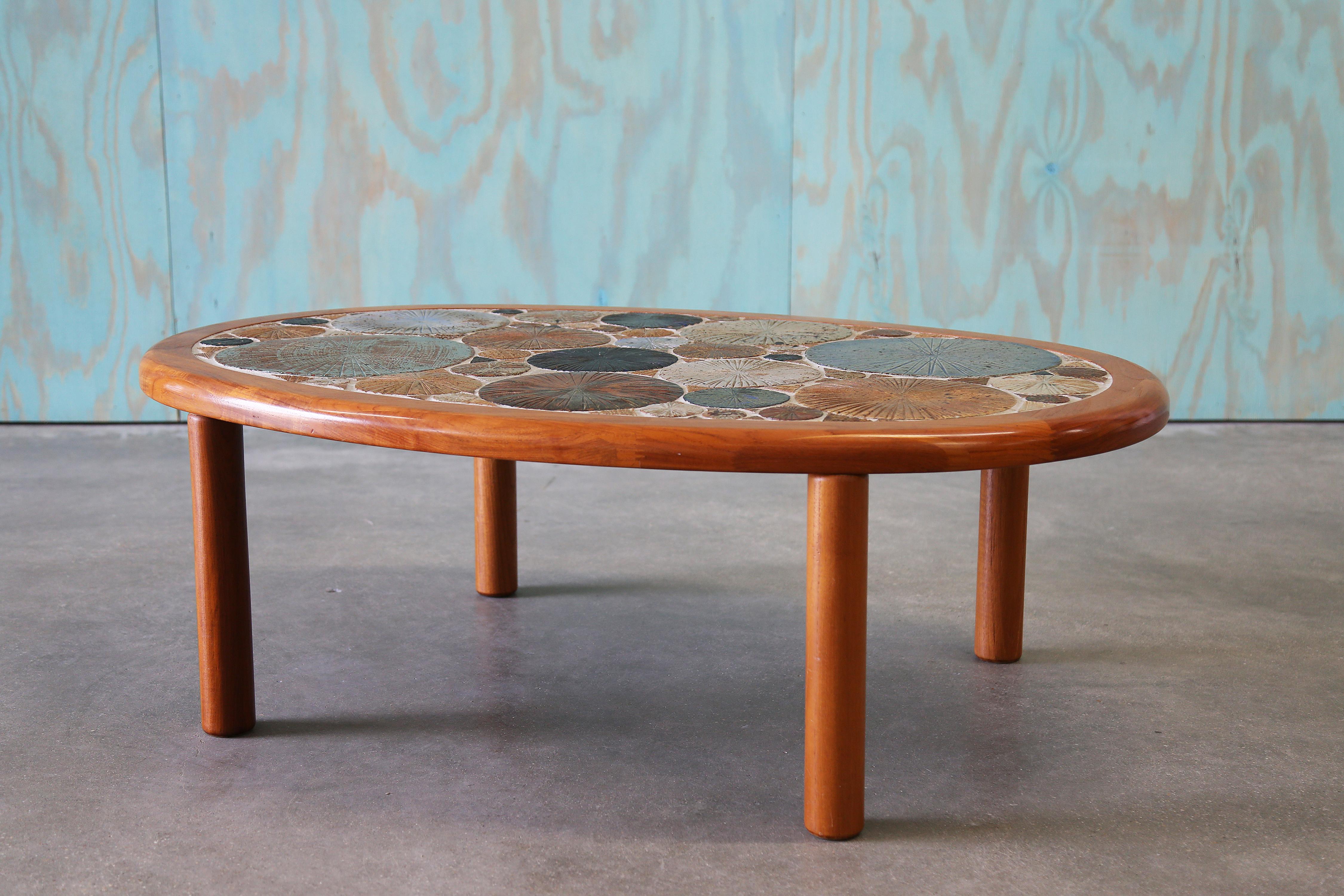 An exceptional example of Danish mid-century craftsmanship, this coffee table was designed by renowned artist Tue Poulsen for Haslev Møbelsnedkeri A/S in 1960. The piece features a richly stained teak frame with a sculptural rim, showcasing
