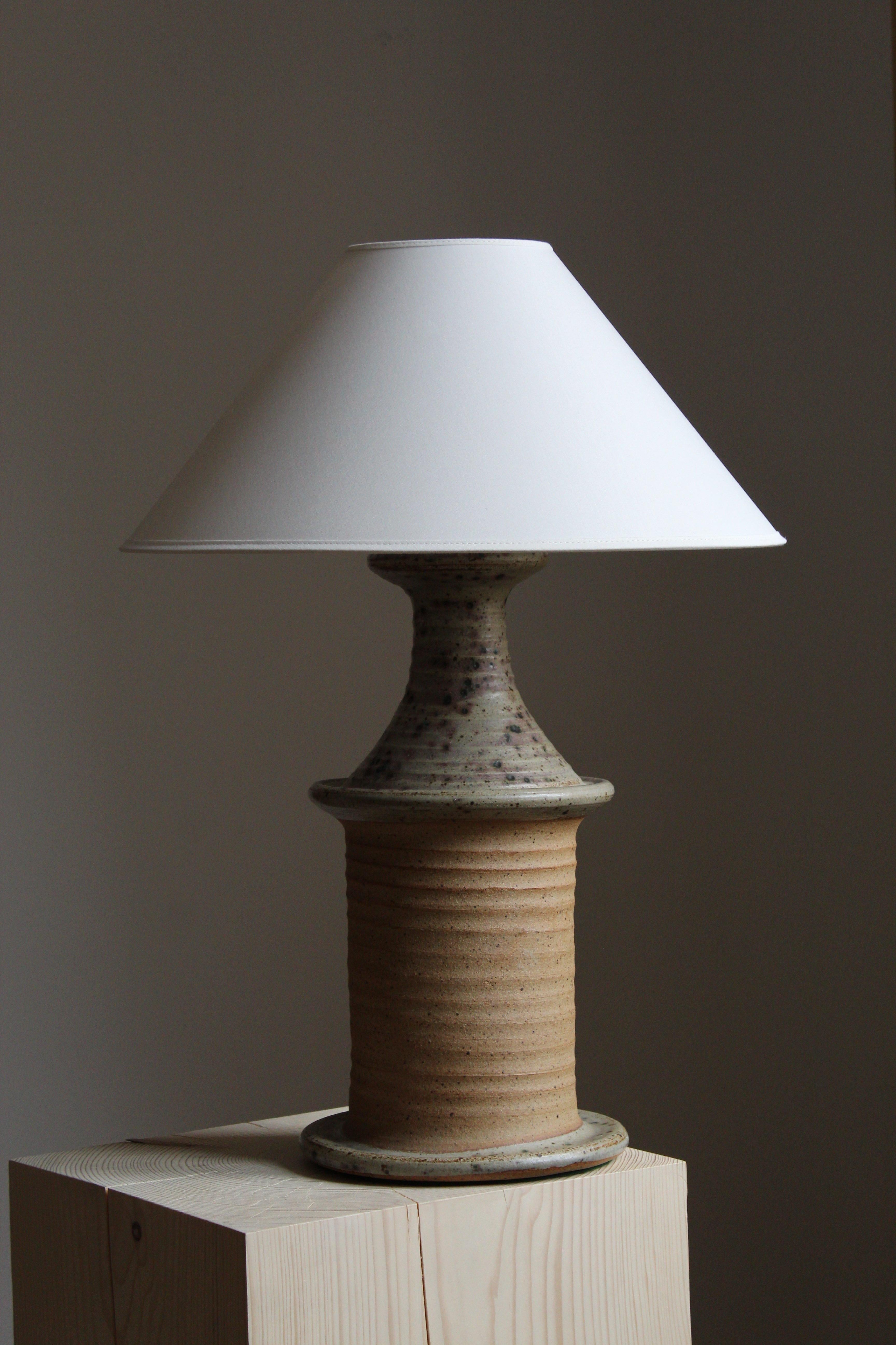 A sizable and sculptural table lamp. Produced and designed by Tue Poulsen, Denmark, 1960s. Underside of base stamped.

In grey or beige stoneware. 

Sold without lampshade. Stated dimensions exclude lampshade.

Other designers of the period
