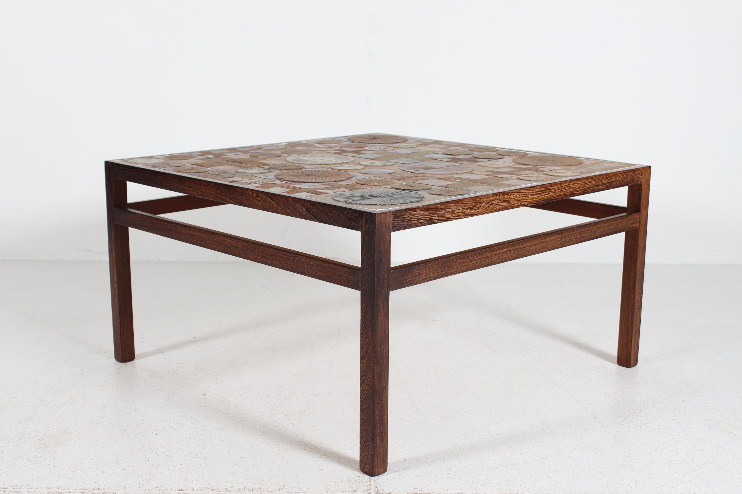 Quadratischer Couchtisch des dänischen Künstlers und Keramikers Tue Poulsen (geb. 1939) und des dänischen Möbeldesigners Erik Wørts (1916-97). Hergestellt ca. 1960er Jahre.
Auf dem Couchtisch befinden sich handgefertigte Fliesen aus Tue Poulsens
