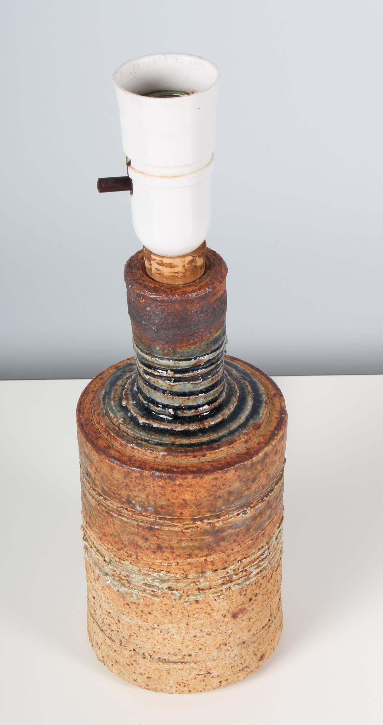 1960s wheel thrown stoneware tablelamp by Danish ceramist Tue Poulsen. Clear glazed speckled neutral stoneware clay body with incised horizontal design work over iron oxide colorant. Stamped underside “Tue Denmark”.

 