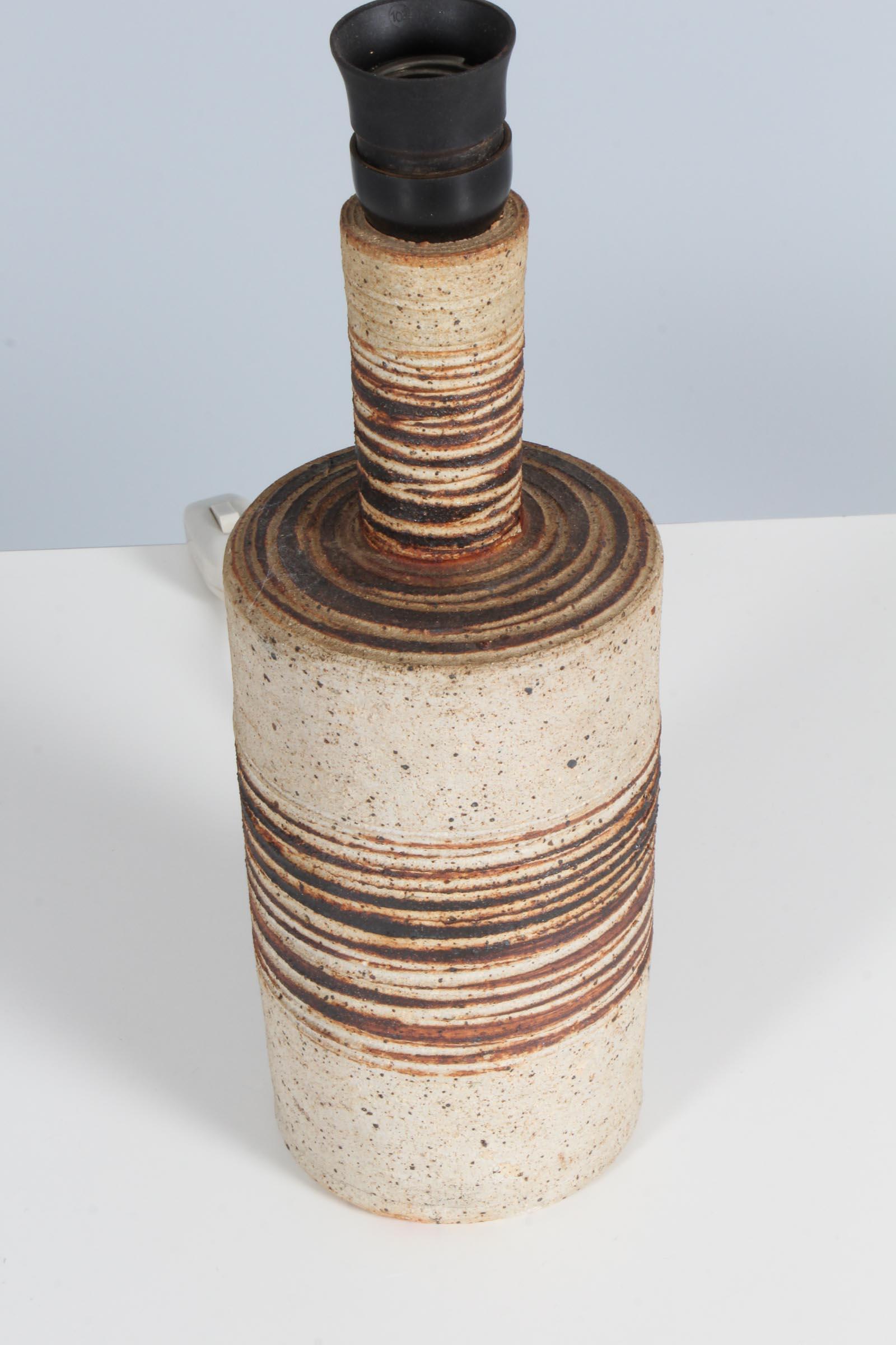 1960er Jahre Tischlampe aus Steingut, radgedreht, vom dänischen Keramiker Tue Poulsen. Klar glasierter, gesprenkelter, neutraler Steingut-Tonkörper mit eingeschnittenem, horizontalem Muster über Eisenoxid-Farbstoff. Unterseite gestempelt 