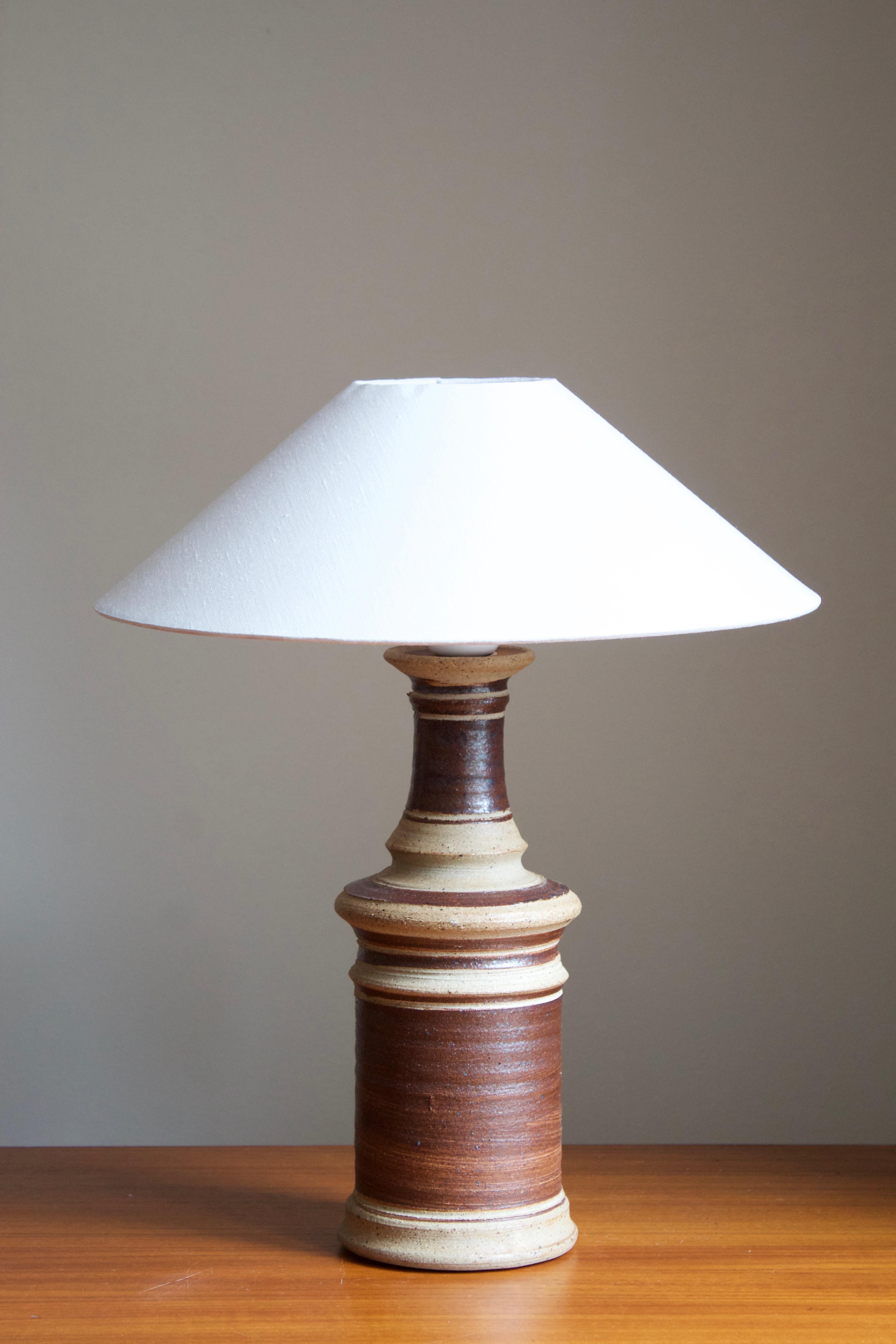 A sizable table lamp. Produced and designed by Tue Poulsen, Denmark, 1960s. Underside of base stamped.

Sold without lampshade. Stated dimensions exclude lampshade. 

Glaze features brown-grey colors.

Other designers of the period include Axel