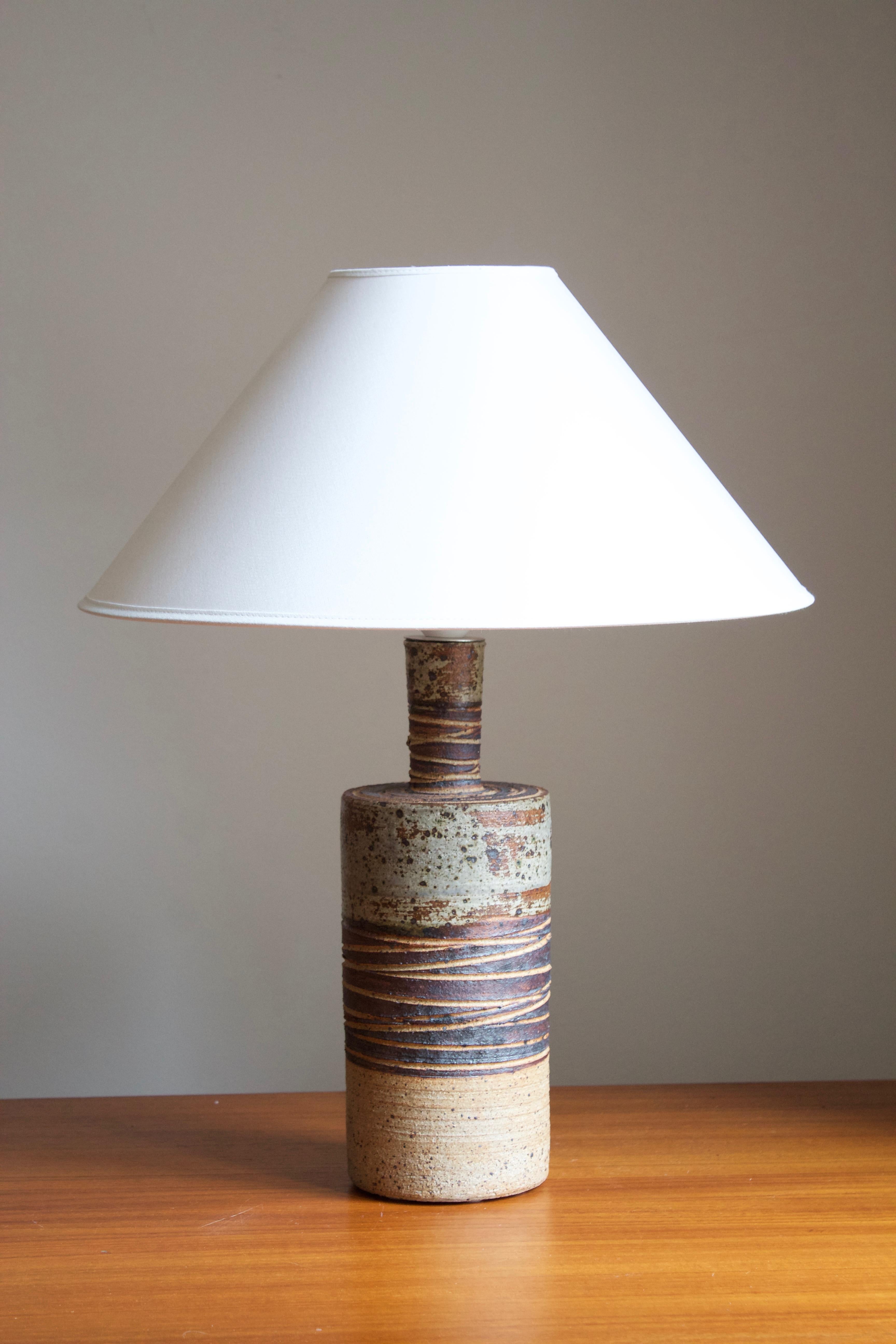 A sizable table lamp. Produced and designed by Tue Poulsen, Denmark, 1960s. Underside of base stamped.

Sold without lampshade. Stated dimensions exclude lampshade. 

Glaze features brown-beige-green colors.

Other designers of the period include