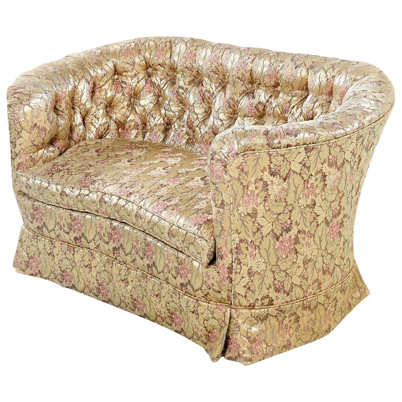 This lovely French tufted settee canapé couch features champagne colored upholstery embellished with a floral motif. The pink flowers contrast against the satiny, iridescent light beige colored background. Button tufting on the backrest adds an air