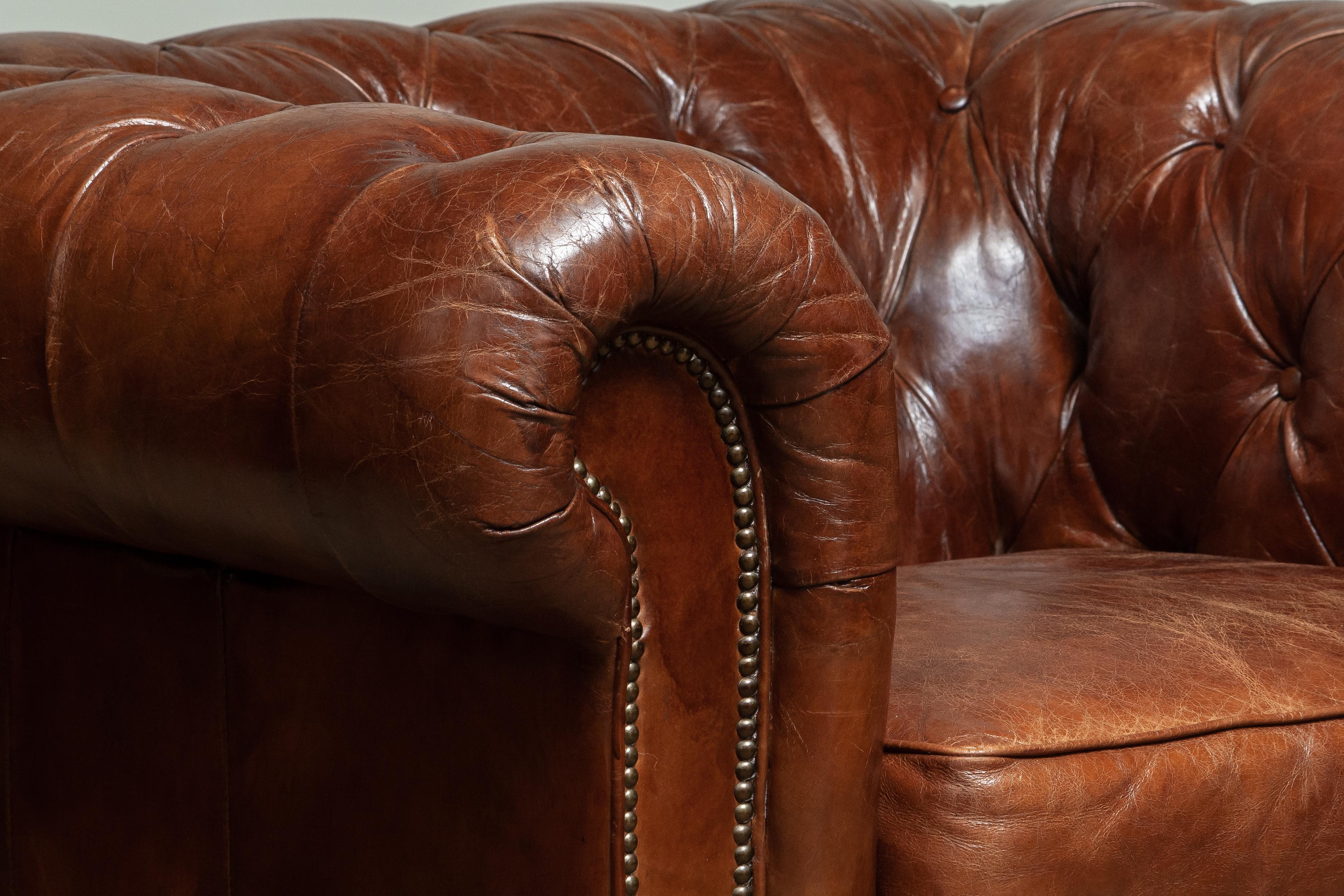 Chesterfield lounge / easy chair in chocolate brown leather with a beautiful patina true the years.
Underneath the seat cushion, filled with feather, is fully sprung therefor the seat is soft and comfortable.
The overall condition in good.
Note