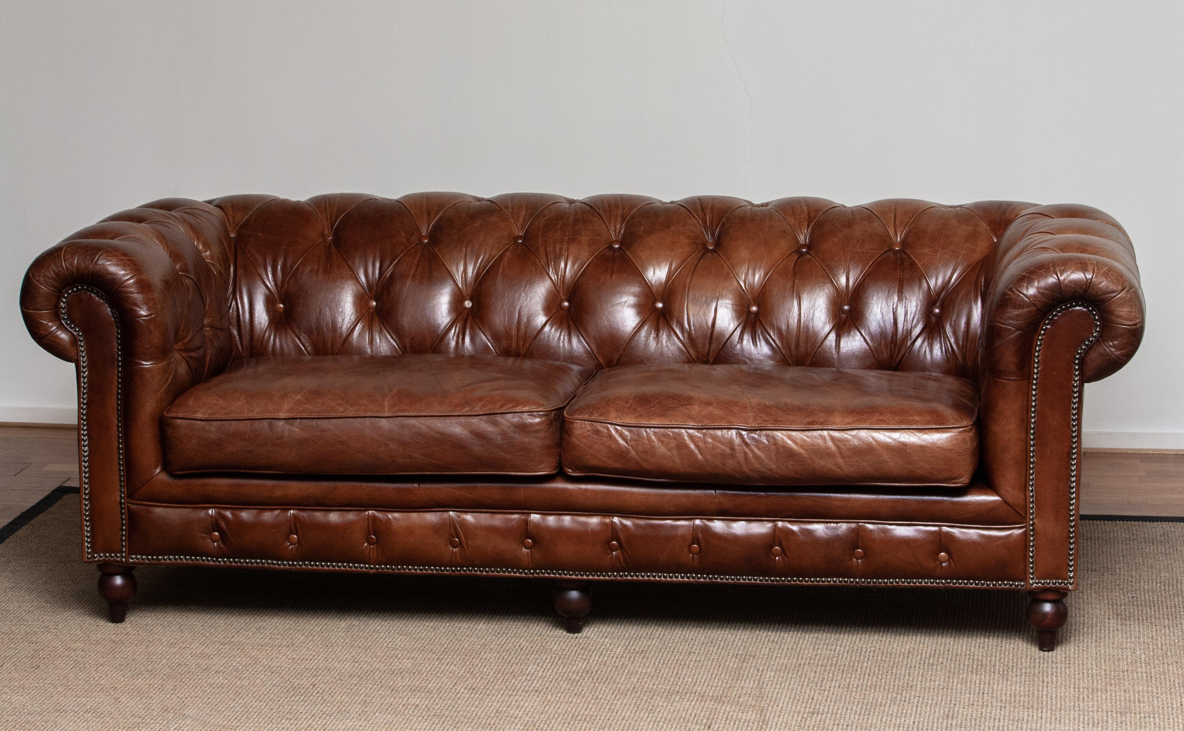Chesterfield sofa in chocolate brown leather with a beautiful patina true the years. 
Underneath the seat cushions, filled with feather, is fully sprung therefor the seat is soft and comfortable. 
The overall condition in good.
 