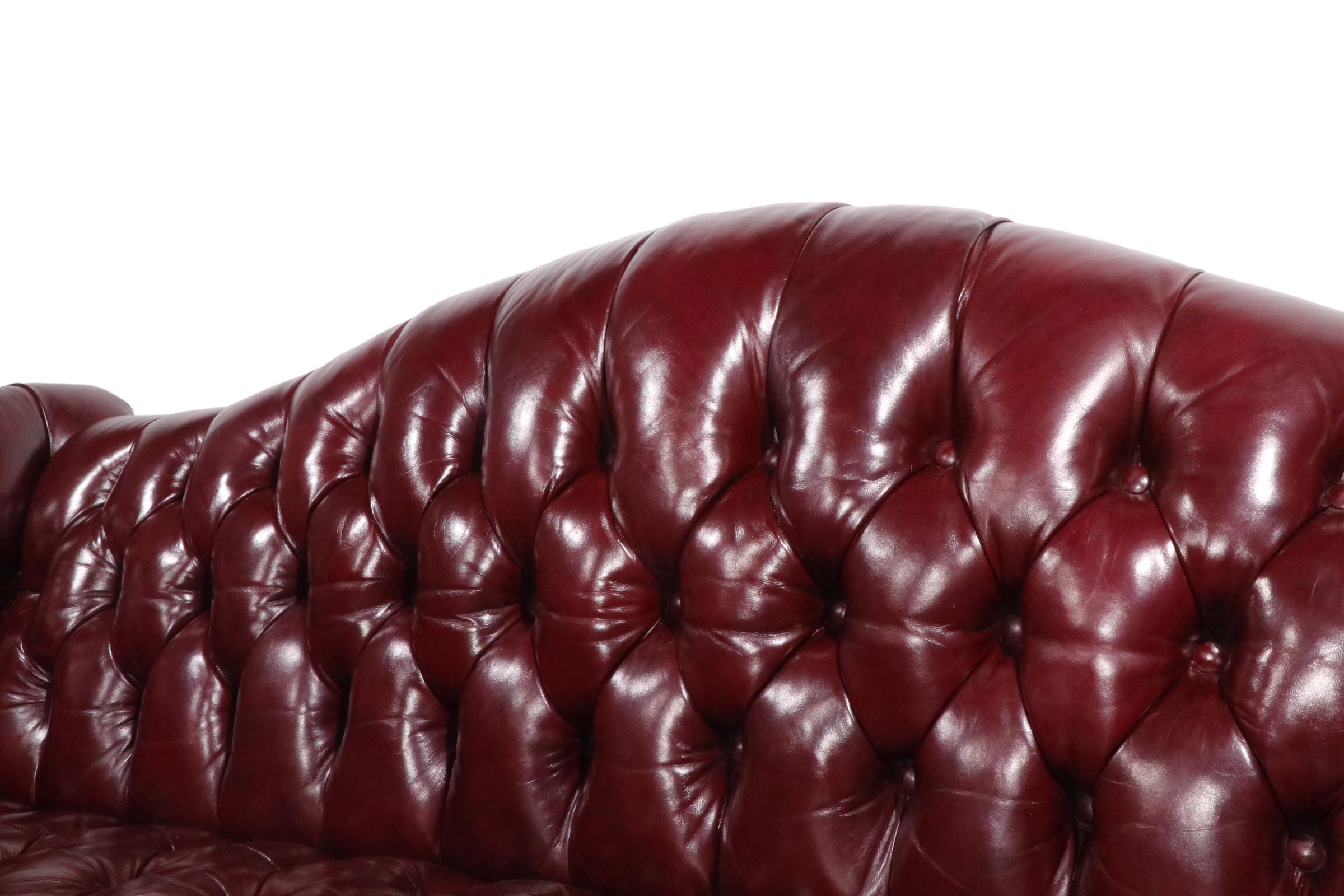 Außergewöhnliches Kamelrückensofa im Chippendale-Stil aus bordeauxfarbenem Ledersofa. Dieses atemberaubende Sofa zeichnet sich durch eine vollständig getuftete Oberfläche, geschnitzte Beine aus Mahagoni im Marlborough-Stil, gebundene Federpolsterung